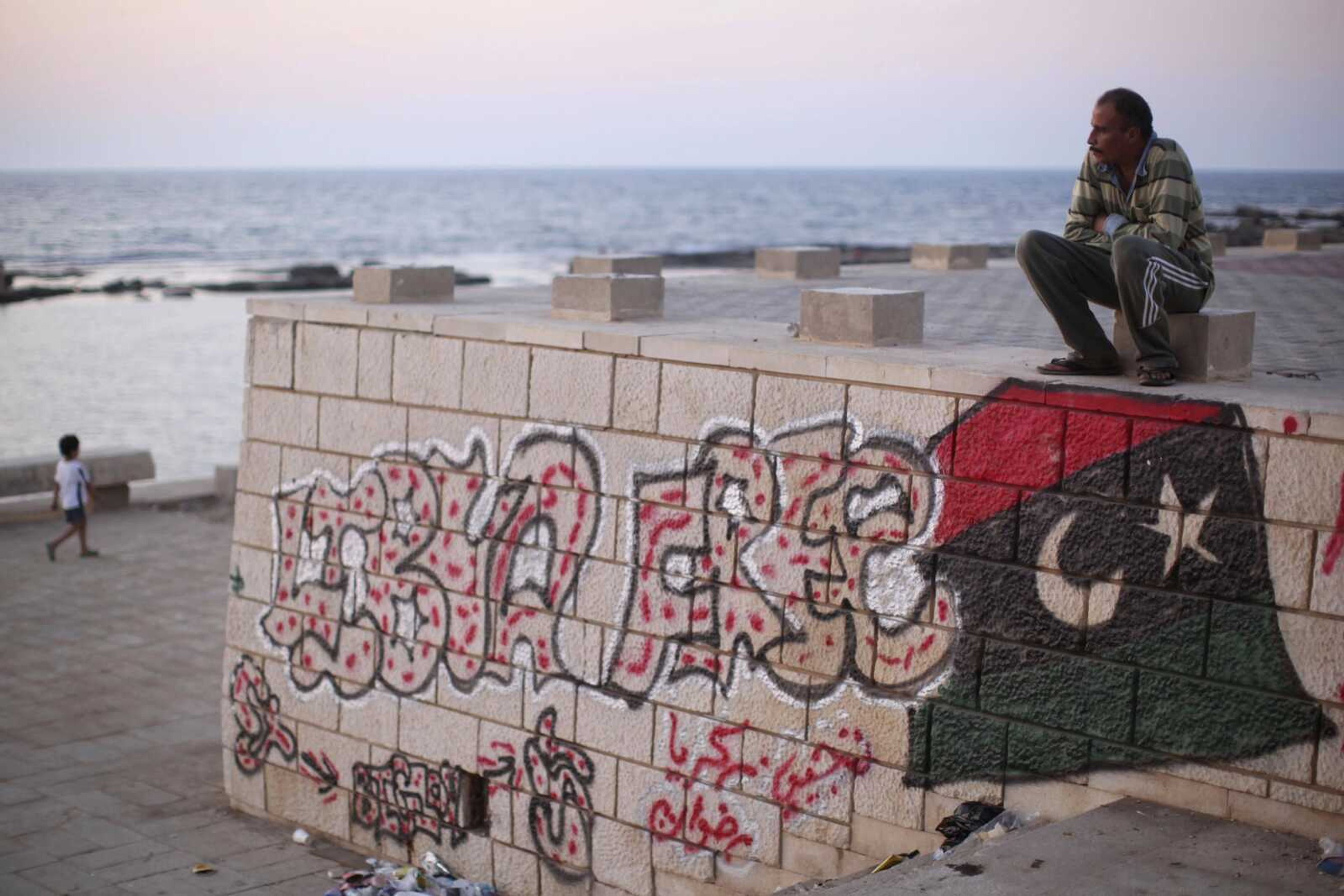 Painter Rafat Askar, 46, rests Thursday at the seaside of the rebel-held town of Benghazi, Libya. The paint on the wall reads &#8220;Libya Free.&#8221; (Alexandre Meneghini ~ The Associated Press)