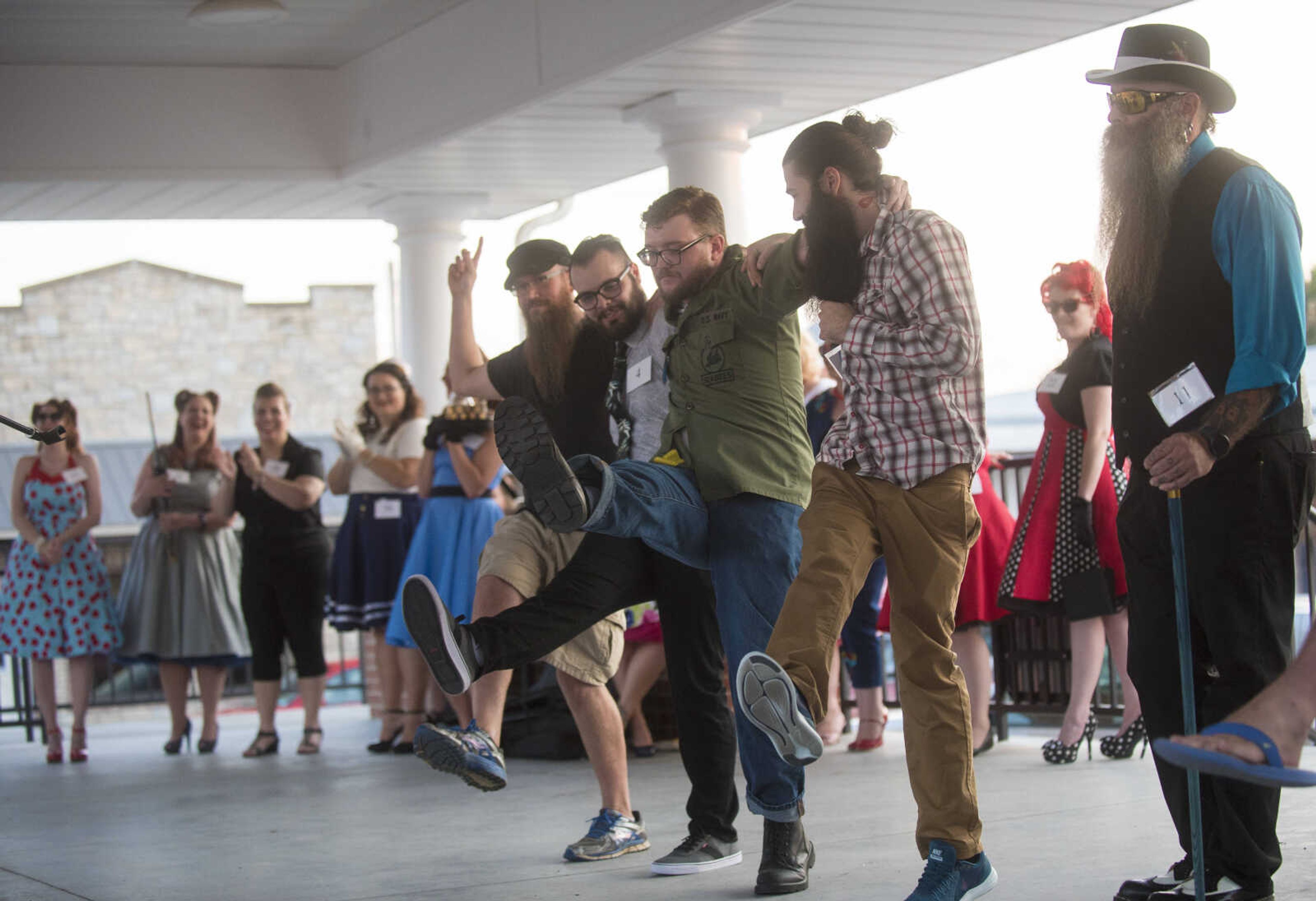 Bearded men kick their feet after the facial hair contest during the Perryville Pinup contest Saturday, Sept. 2, 2017 in downtown Perryville.