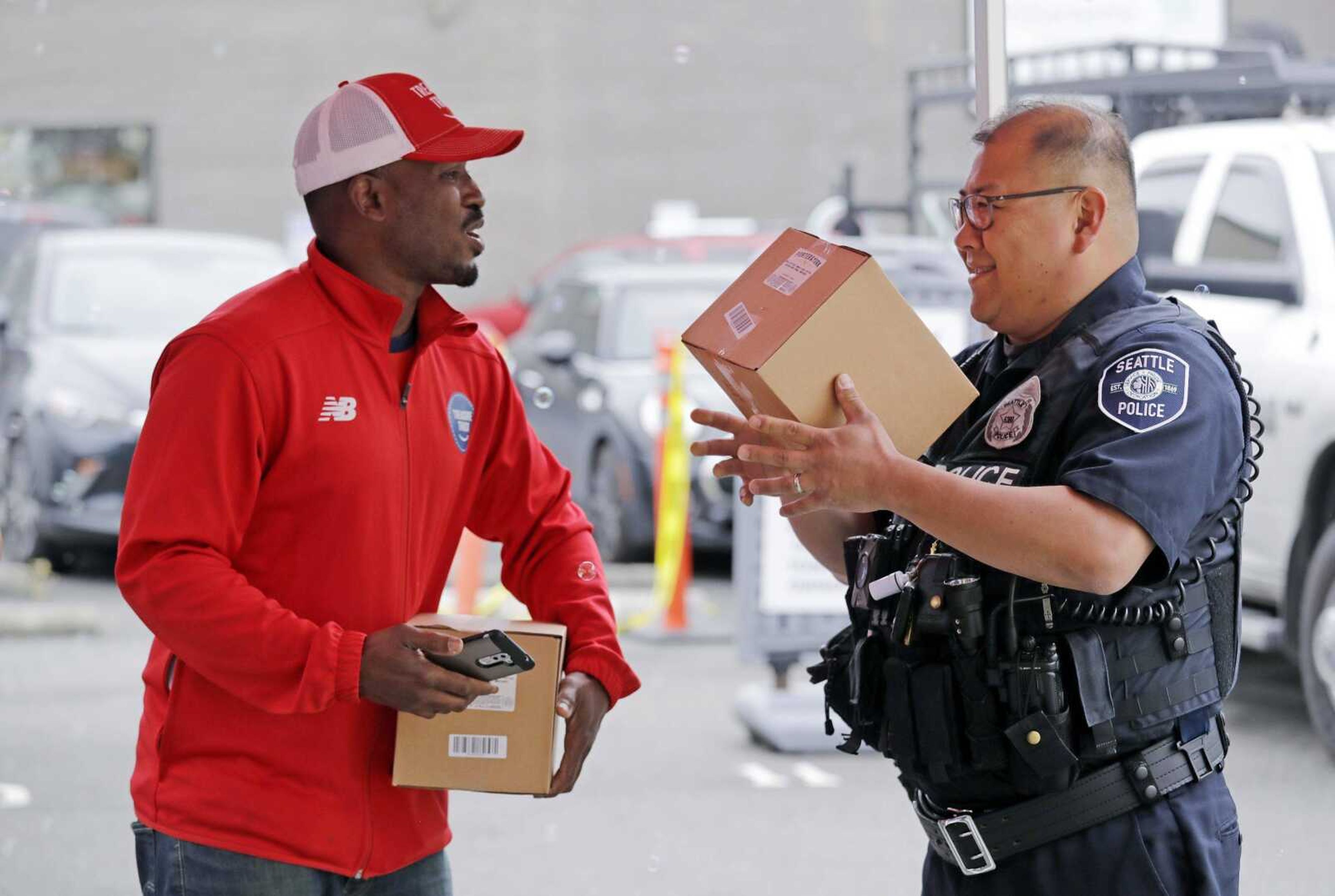 Amazon worker Khayyam Kain, left, hands off a package to Seattle police officer Pablo Lee on May 24 at an Amazon Treasure Truck in Seattle. The Treasure Truck is a quirky way for the online retailer to connect with shoppers in person, expand its physical presence and promote itself. The trucks debuted two years ago and now roam nearly dozens of cities in the United States and England.