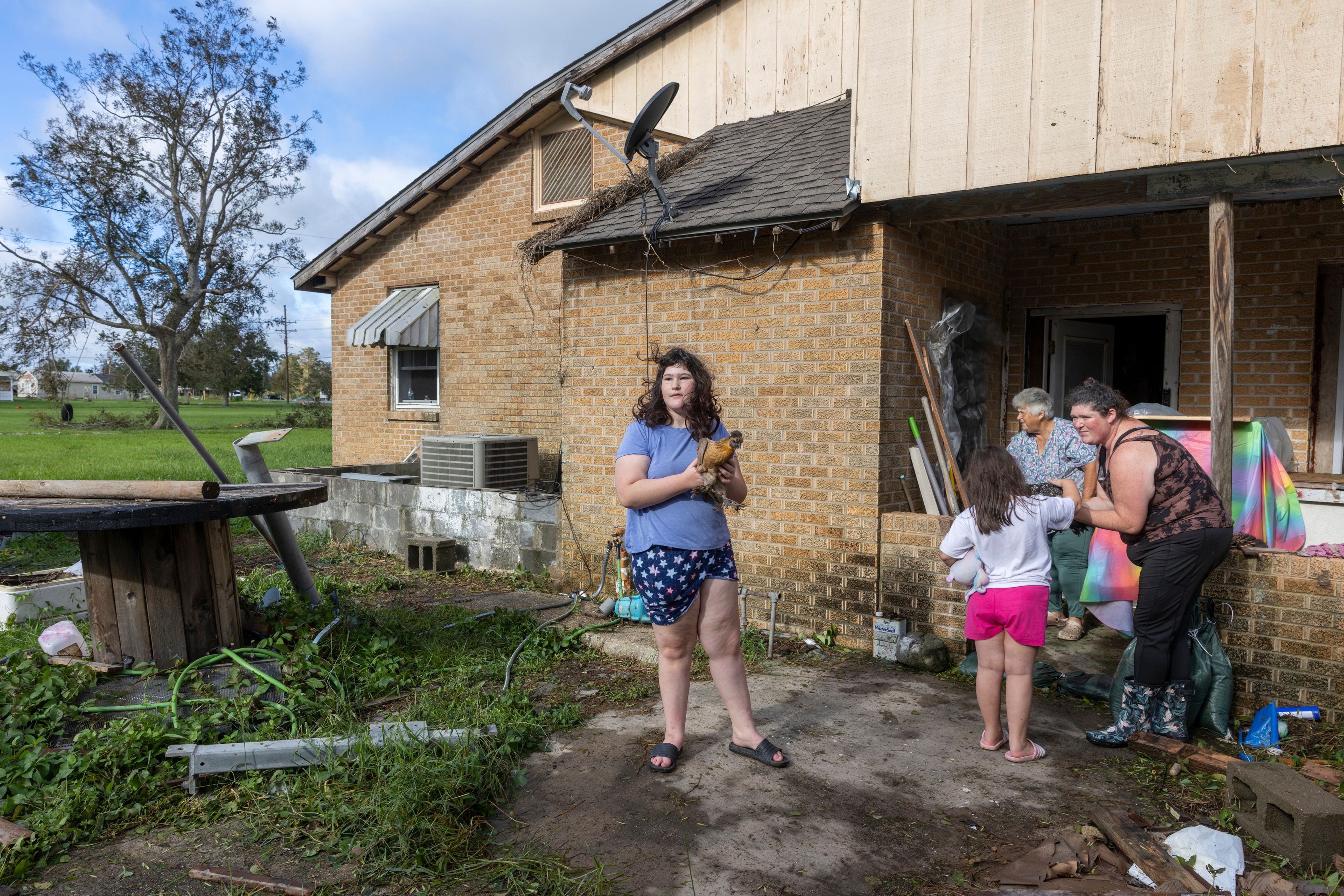 Bailee Boudreaux, 14, center, and her family bring out the chickens they let sleep in their house during the height of Hurricane Francine in Houma, La., Thursday, Sept. 12, 2024. (Chris Granger/The Times-Picayune/The New Orleans Advocate via AP)