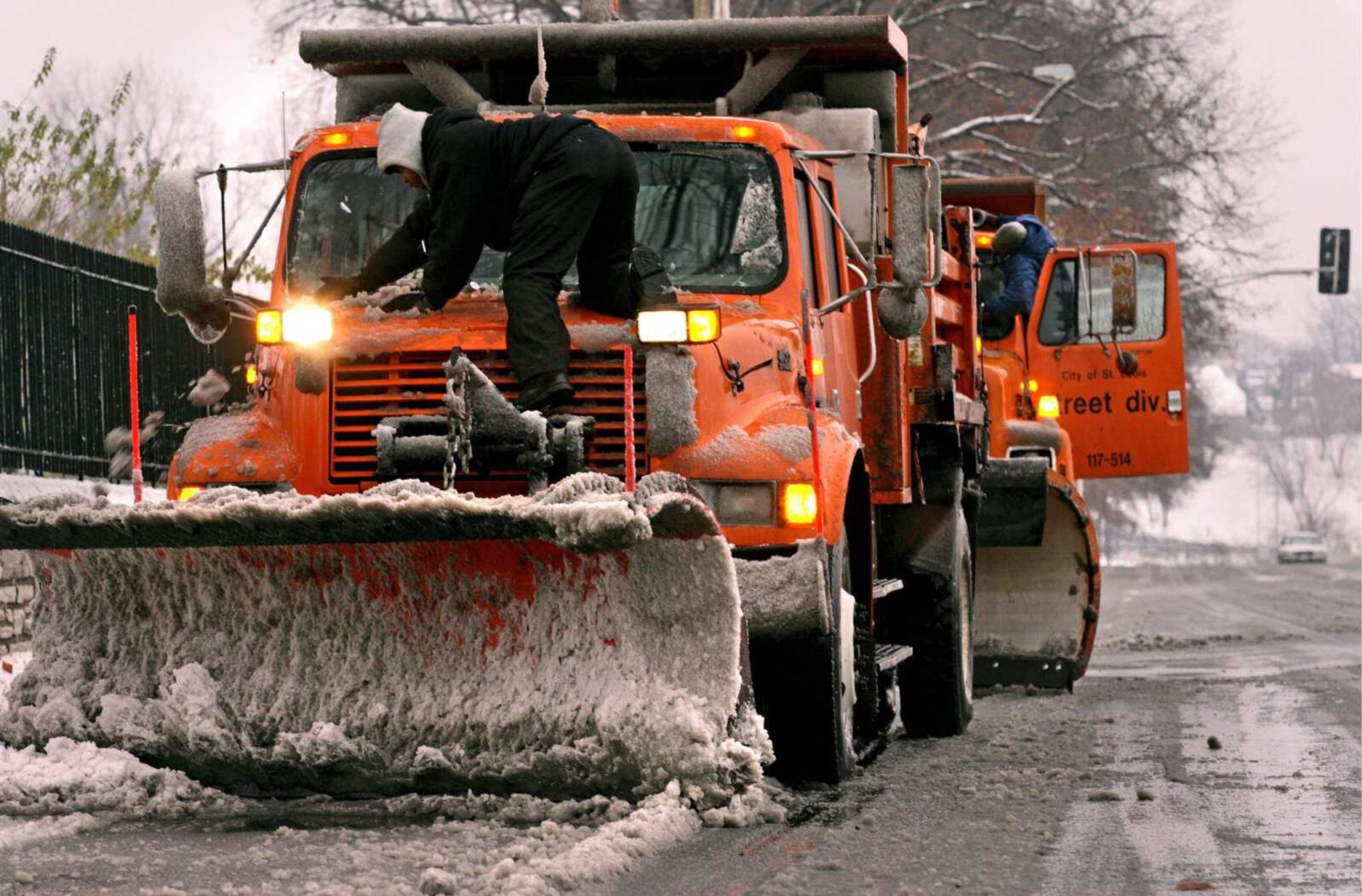 St. Louis city workers Marvis Thomas, left, and Terrance Benson pulled over to clear snow from their trucks while clearing a street Saturday in St. Louis after snow covered the city. (Christian Gooden ~ St. Louis Post-Dispatch)