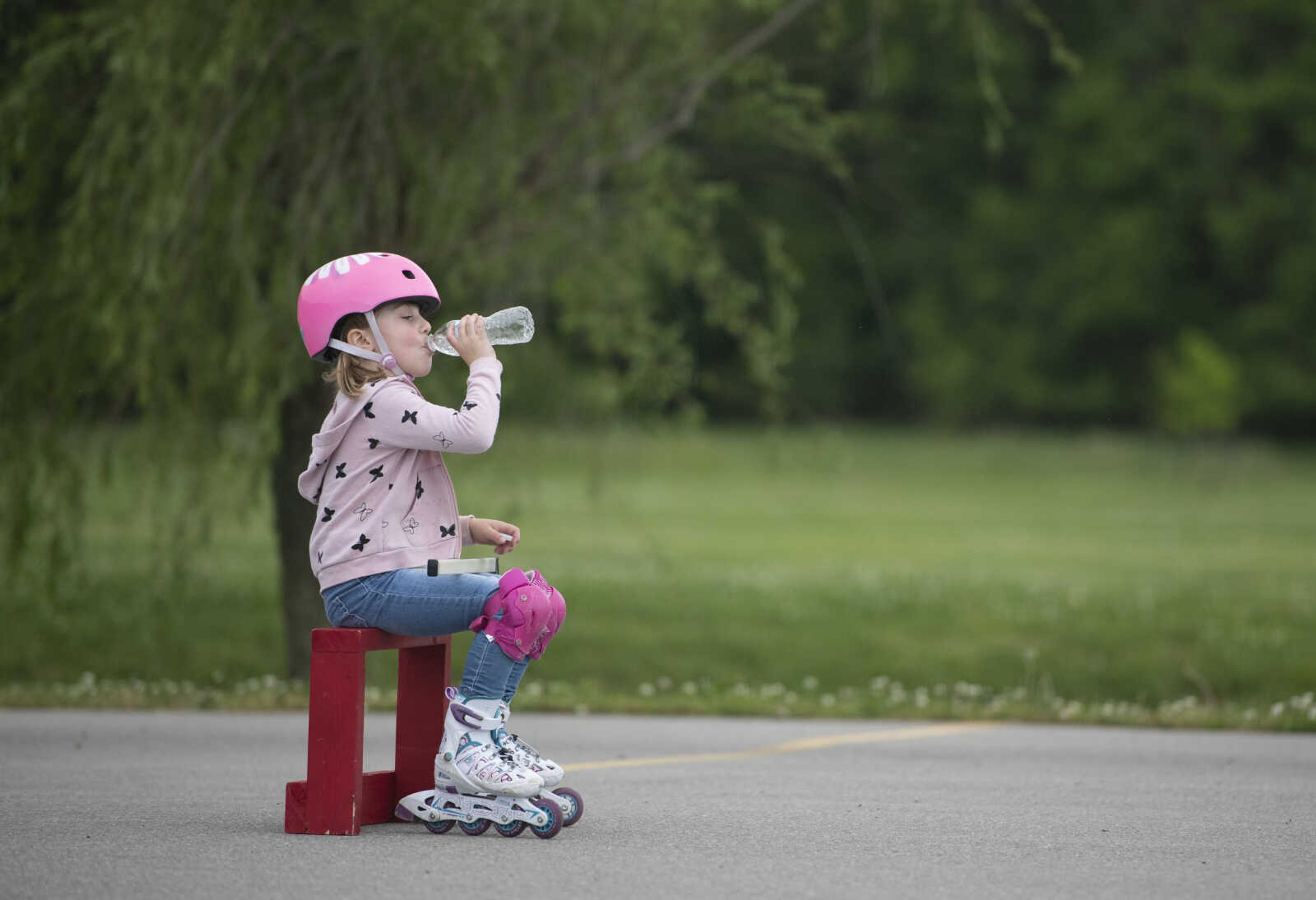 Matilda Booch, 5, takes a drink while playing hockey with family Wednesday, May 20, 2020, at a parking lot near Cape Splash Family Aquatic Center in Cape Girardeau.