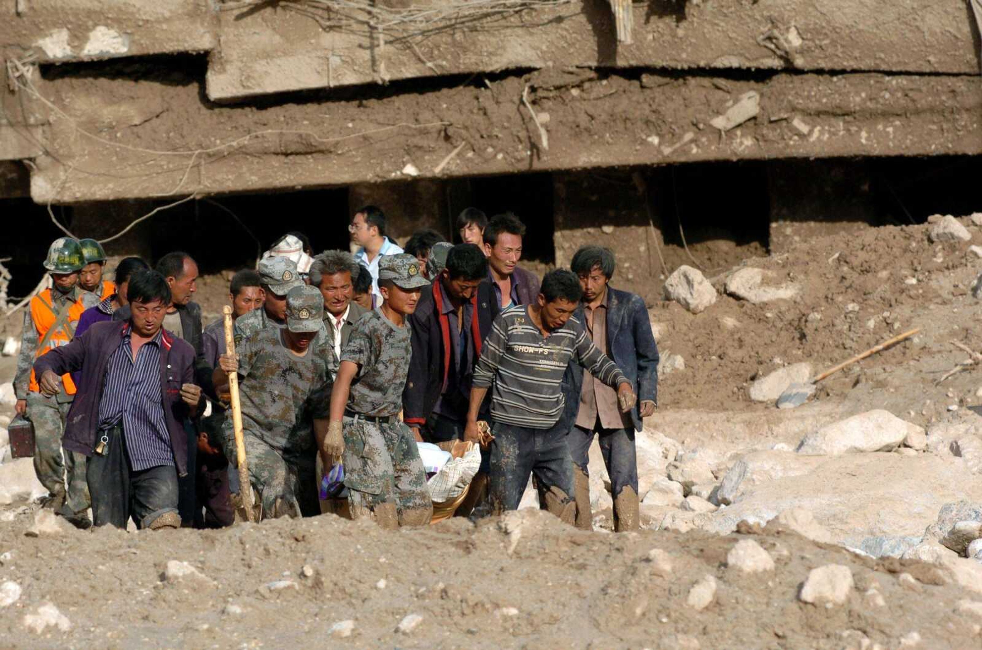 Policemen and residents carry the body of a landslide victim Sunday in northwest China's Gansu Province. Flooding in several Asian nations have left hundreds dead and millions facing food shortages. (Gao Jianjun ~ Xinhua News Agency)