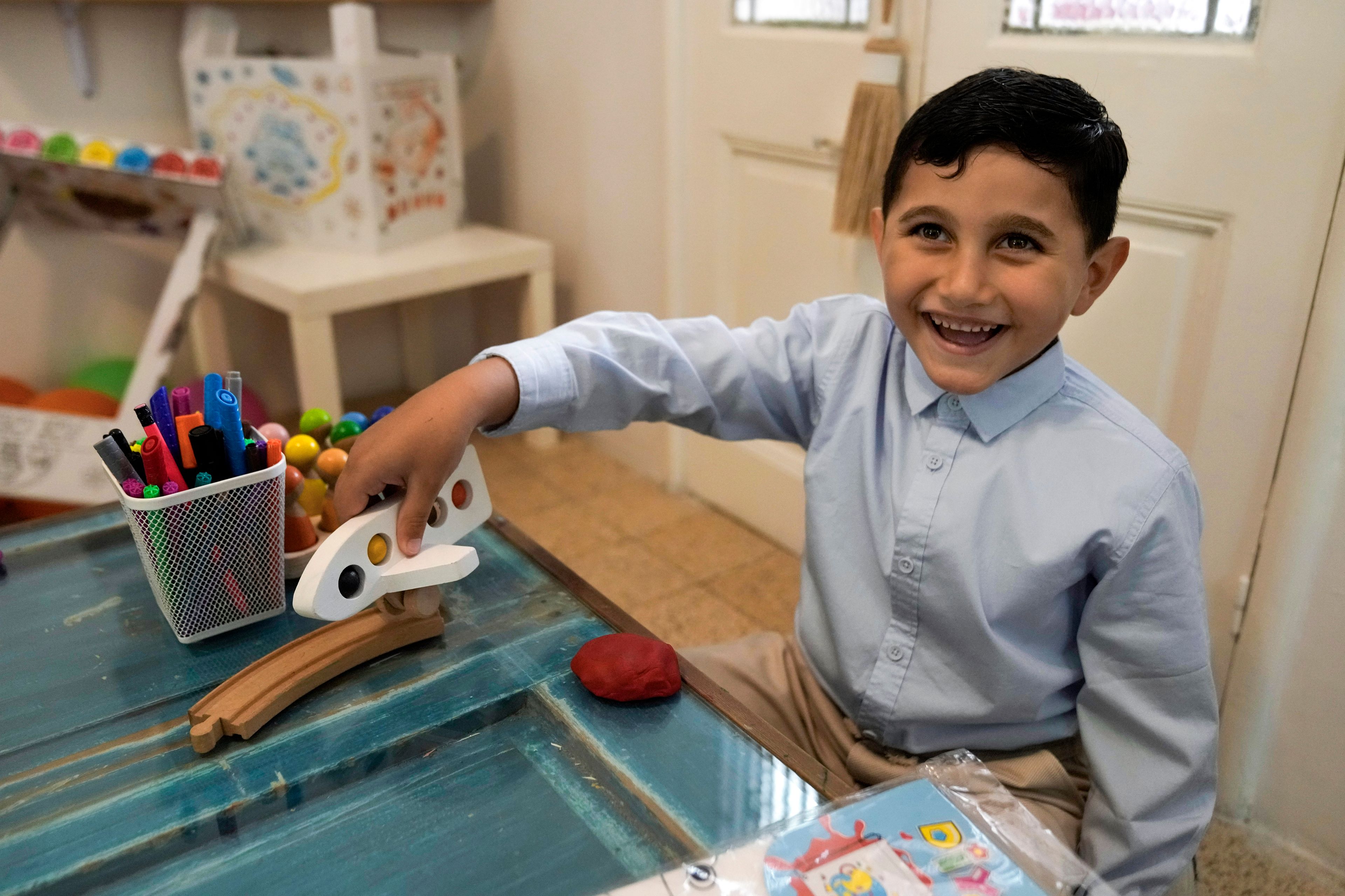 Palestinian Adam Afana, 5, who was brought to Lebanon from Gaza Strip for treatment who had nearly lost his left arm in an Israeli airstrike that killed his father and sister, plays with a toy plane at a summer camp in Beirut, Lebanon, Friday, Aug. 30, 2024. (AP Photo/Bilal Hussein)