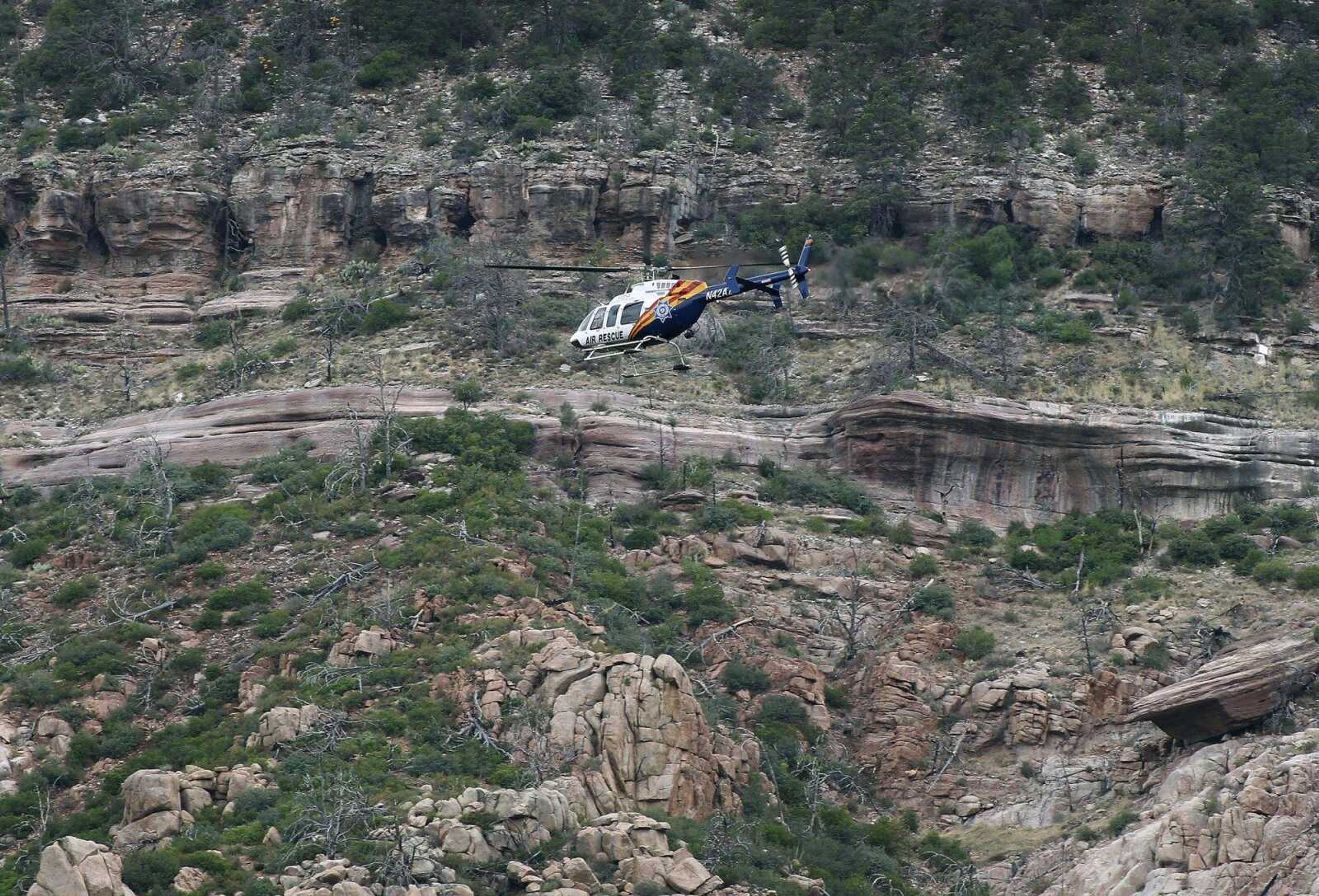 A helicopter flies above the banks of the East Verde River during a search and rescue operation Sunday for victims of a flash flood in Payson, Arizona.