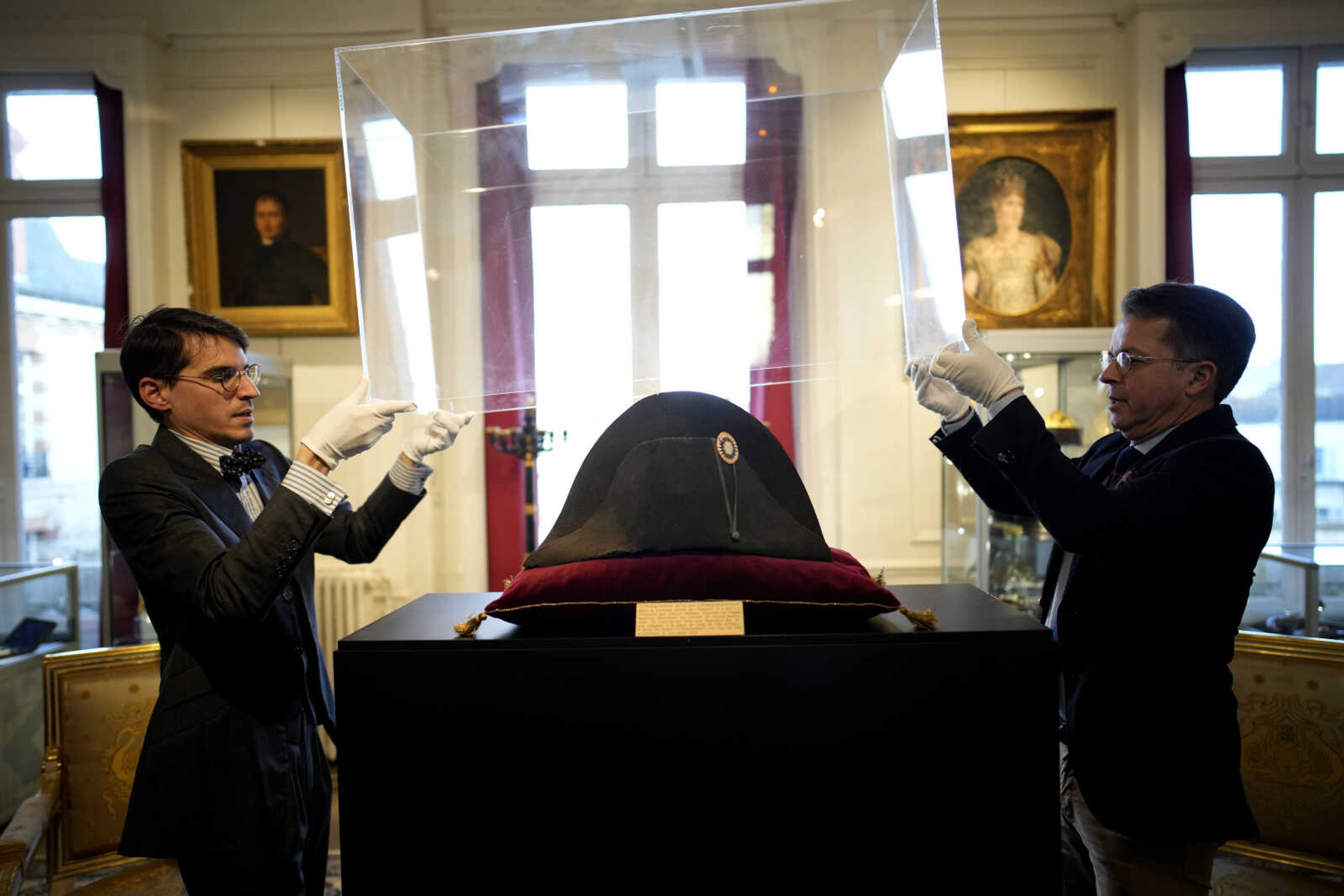 Raphael Pitchal, left, and Jean Christophe Chataignier of Osenat's auction house remove the protection of one of the signature broad, black hats that Napoleon wore when he ruled 19th century France and waged war in Europe at Osenat's auction house in Fontainebleau, south of Paris, Friday, Nov. 17, 2023. The hat is tipped to fetch more than half a million euros (dollars) at the auction Sunday of Napoleonic memorabilia patiently collected by a French industrialist. (AP Photo/Christophe Ena)