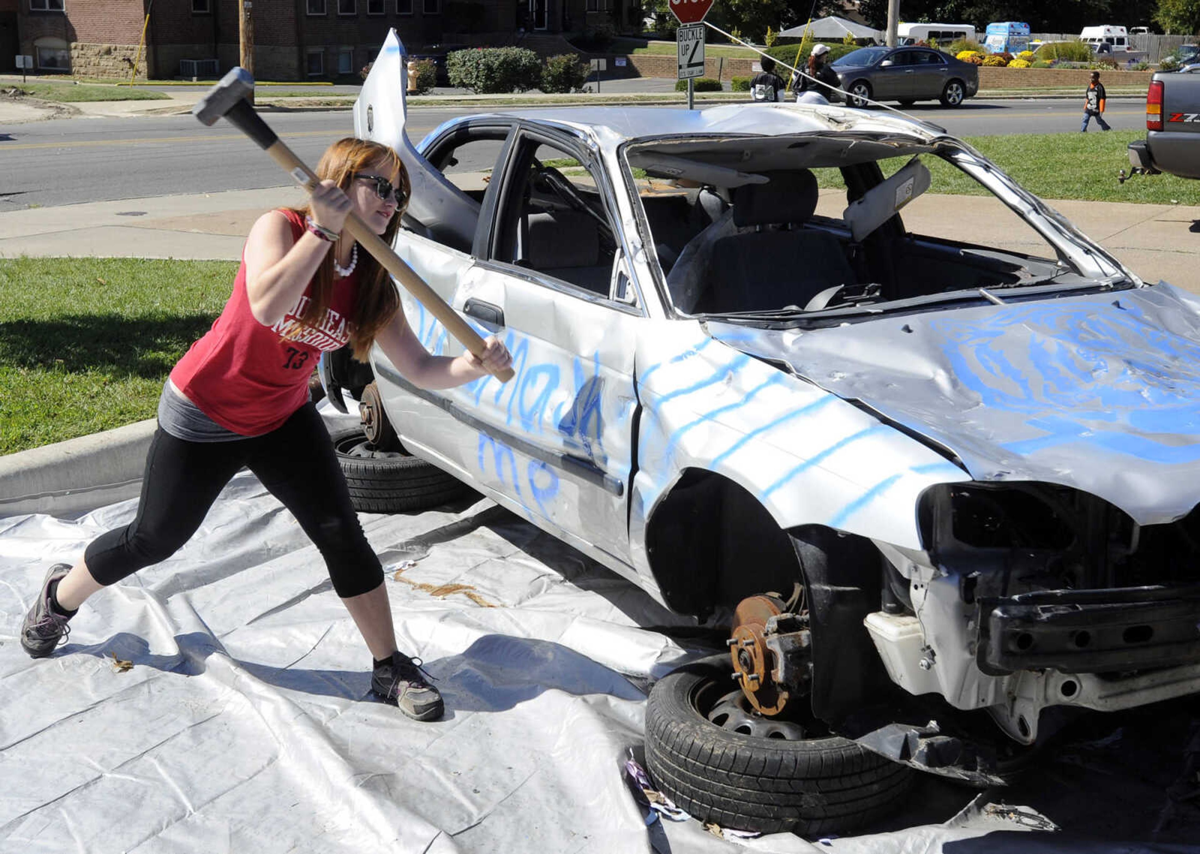 Megan Cooper takes a swing at a junked car at a homecoming tailgate for Southeast Missouri State University on Saturday, Oct. 4, 2014 in Cape Girardeau.