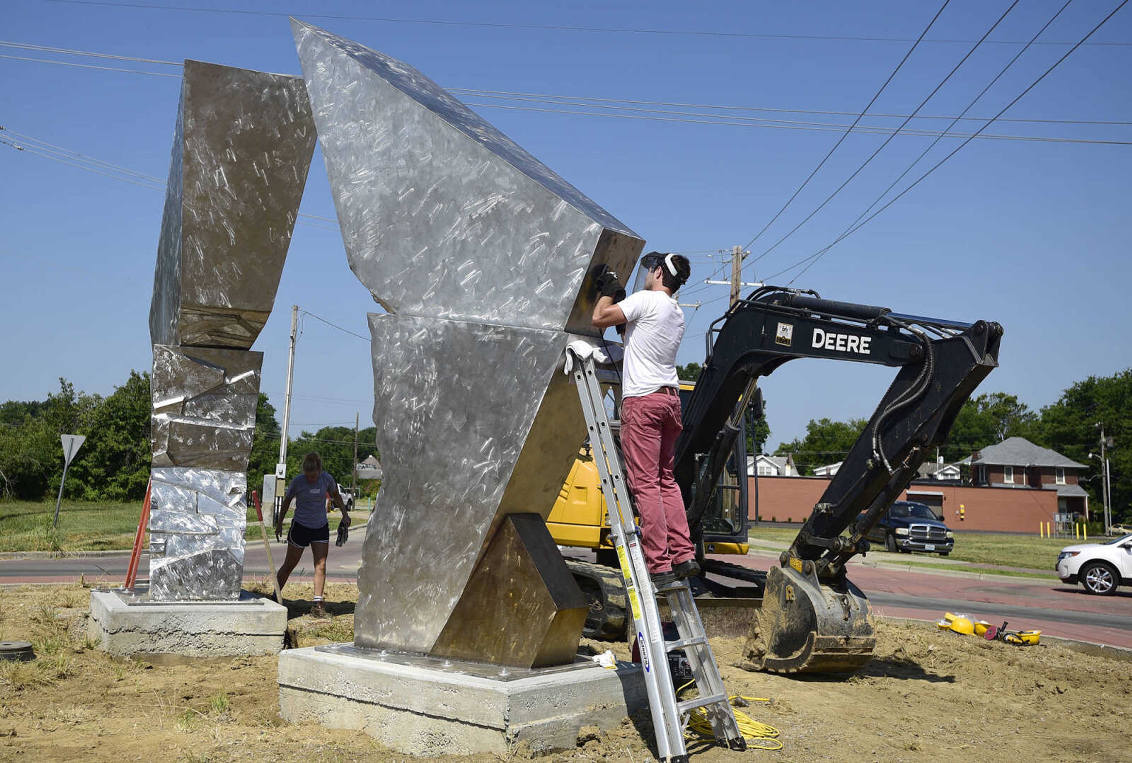 Terry Davis polishes a portion of Chris Wubbena's sculpture, "Commence" after its installation in the Fountain Street roundabout on Monday, July 24, 2017, near the River Campus in Cape Girardeau.