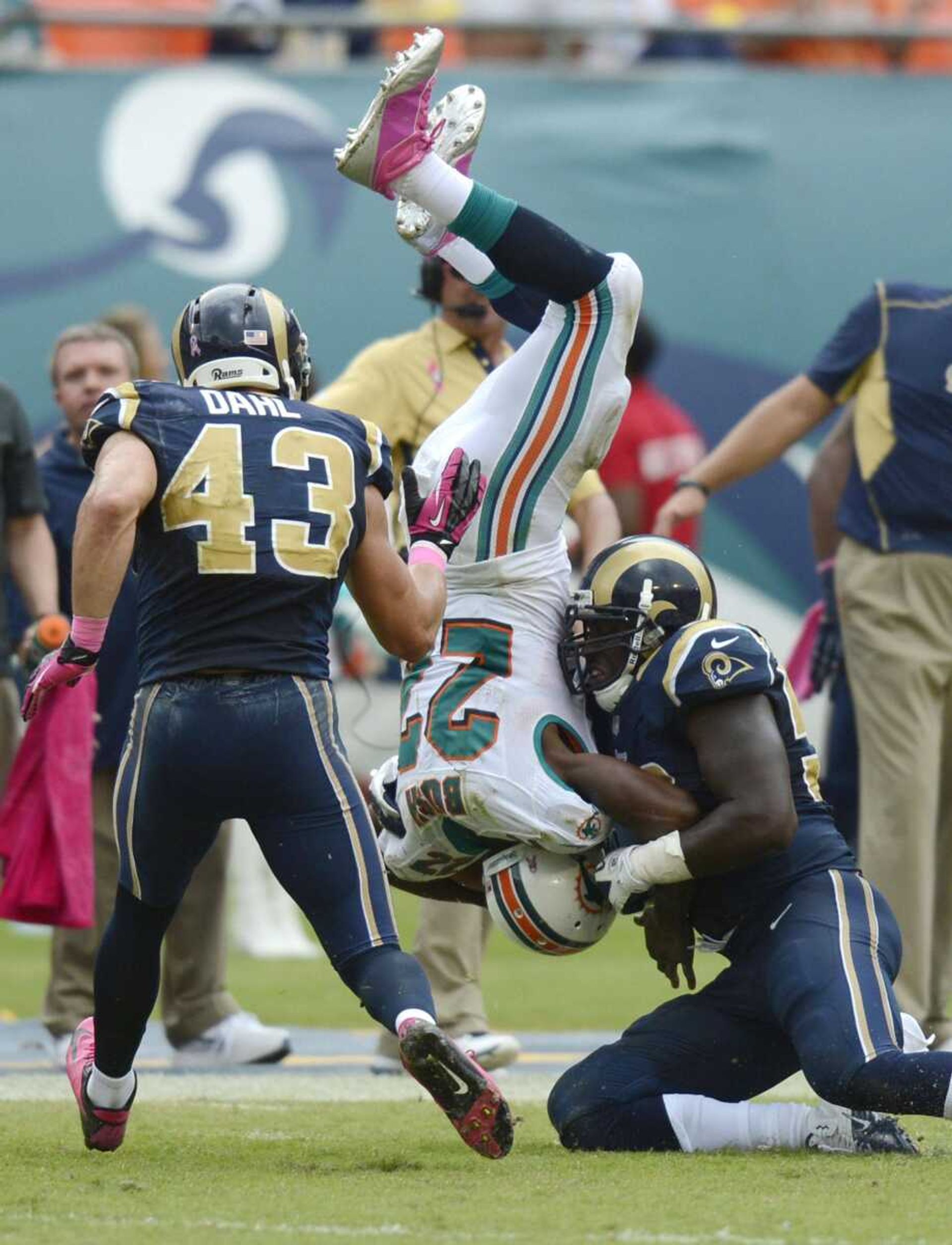 Dolphins running back Reggie Bush is upended during the second half by Rams linebacker Jo-Lonn Dunbar during Sunday&#8217;s game in Miami. The Dolphins won 17-14. At left is Rams strong safety Craig Dahl. (RHONA WISE ~ Associated Press)