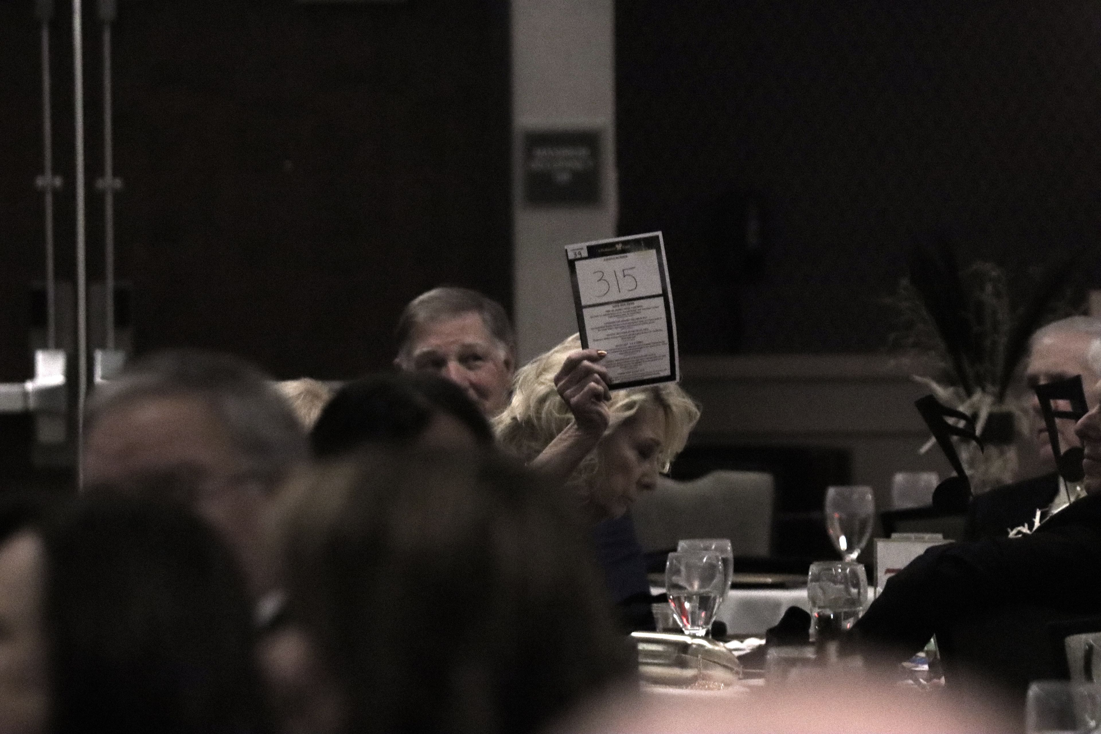 A member of the audience holds up their number to bid on an item at the Lifehouse Gala 