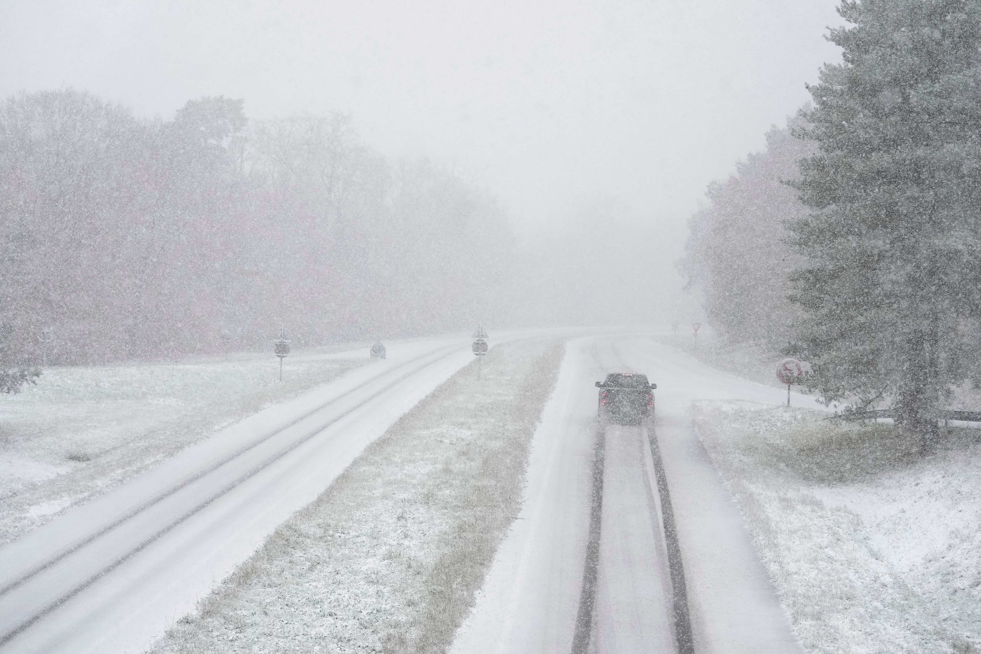 A car drives along a snow-covered road in the forest of Fontainebleau, south of Paris, Thursday, Nov. 21, 2024. (AP Photo/Thibault Camus)