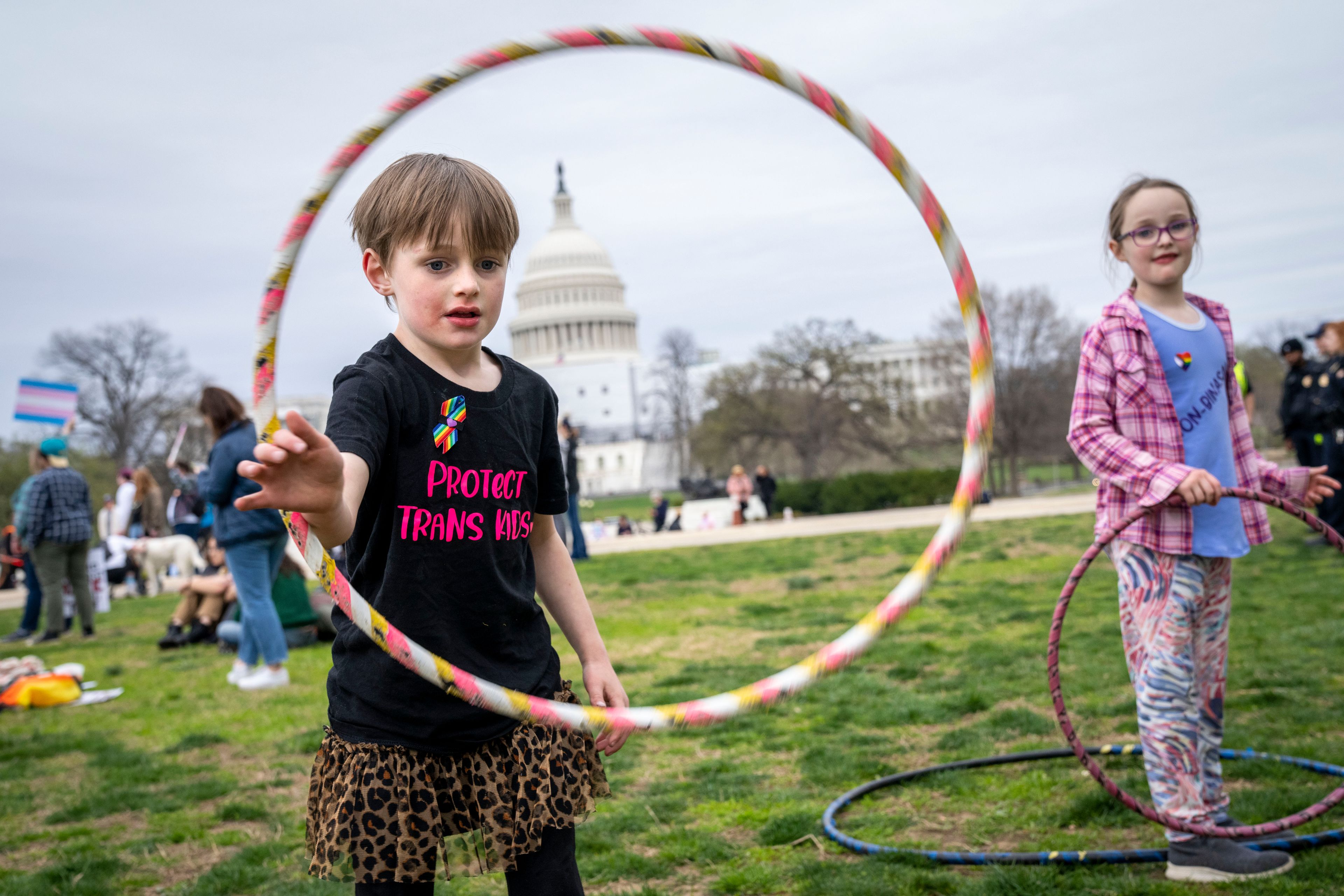 FILE - Mac Gordon Frith, 6, left, who is here supporting his sibling, Caleta Frith, 9, right, who is non-binary, plays with a hula hoop during a rally on the Transgender Day of Visibility, Friday, March 31, 2023, by the Capitol in Washington. (AP Photo/Jacquelyn Martin, File)