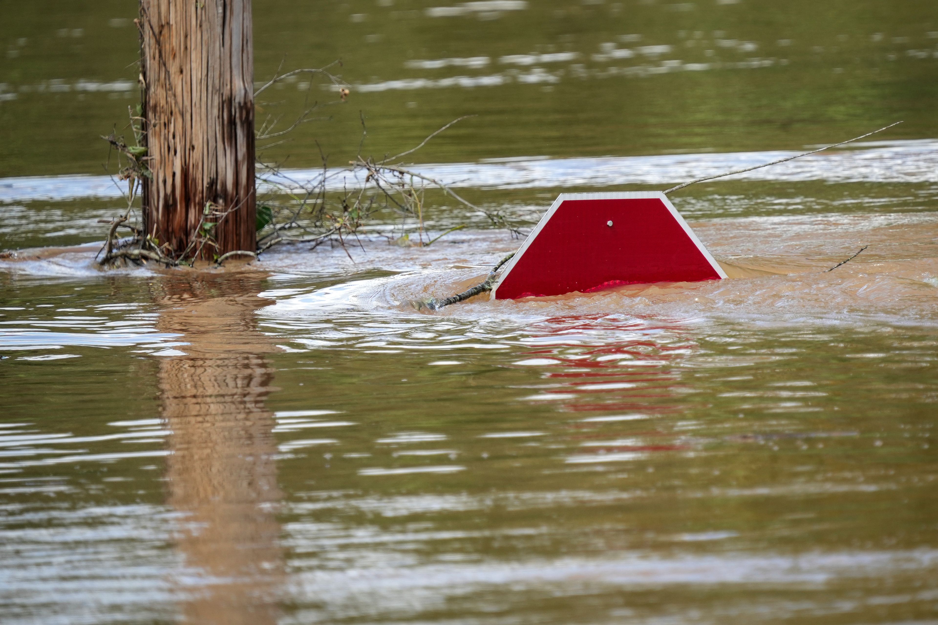 A stop sign can be barely seen above a flooded parking lot after torrential rain from Hurricane Helene caused severe flooding, Saturday, Sept. 28, 2024, in Morganton, N.C. (AP Photo/Kathy Kmonicek)