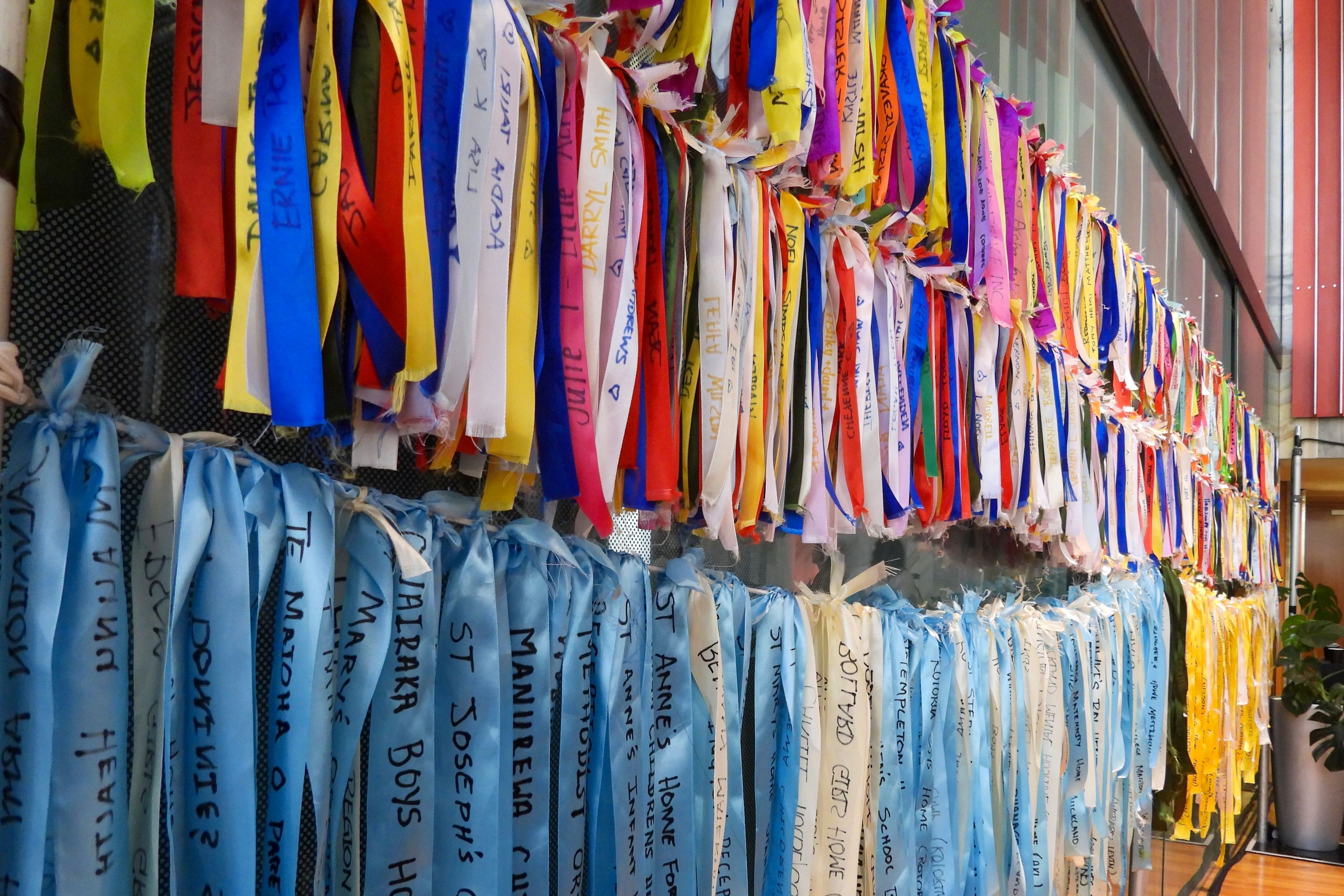 Ribbons are displayed on a wall at Parliament House in Wellington, New Zealand, ahead of the apology to the survivors of abuse in state, faith-based and foster care over a period of seven decades, Tuesday, Nov. 12, 2024. (AP Photo/Charlotte Graham-McLay )