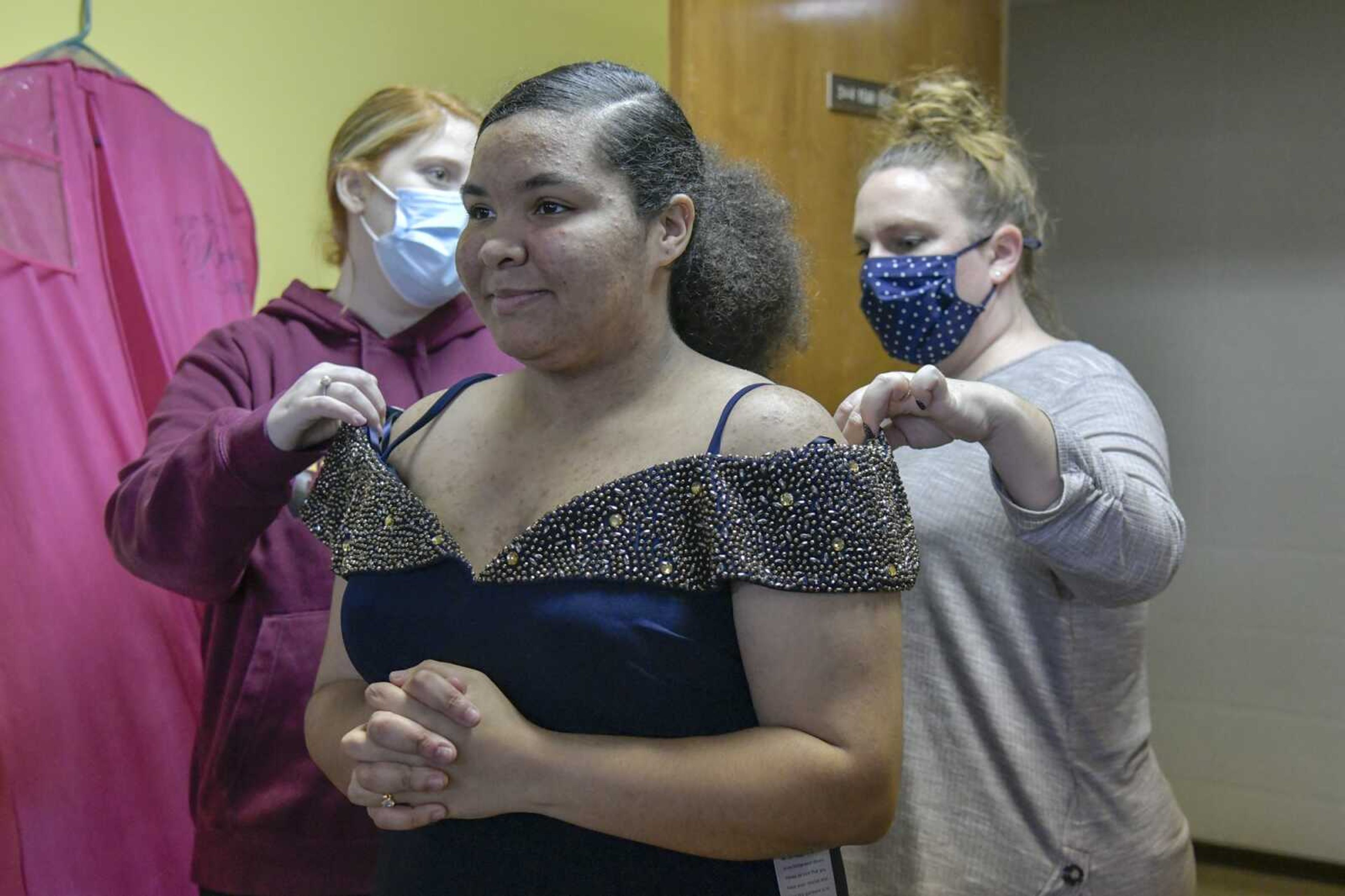 Ivionna Howard, front, stands still while Kelly High School teachers, from back left, Kelly Sloan and Lindsey Limbaugh check to see if the dress she picked out fits her correctly at the SEMO Prom Mothers shop at Westminster Presbyterian Church in Cape Girardeau on Monday, March 15, 2021. Sloan and Limbaugh drove Howard after school to her appointment so she could pick out a dress.