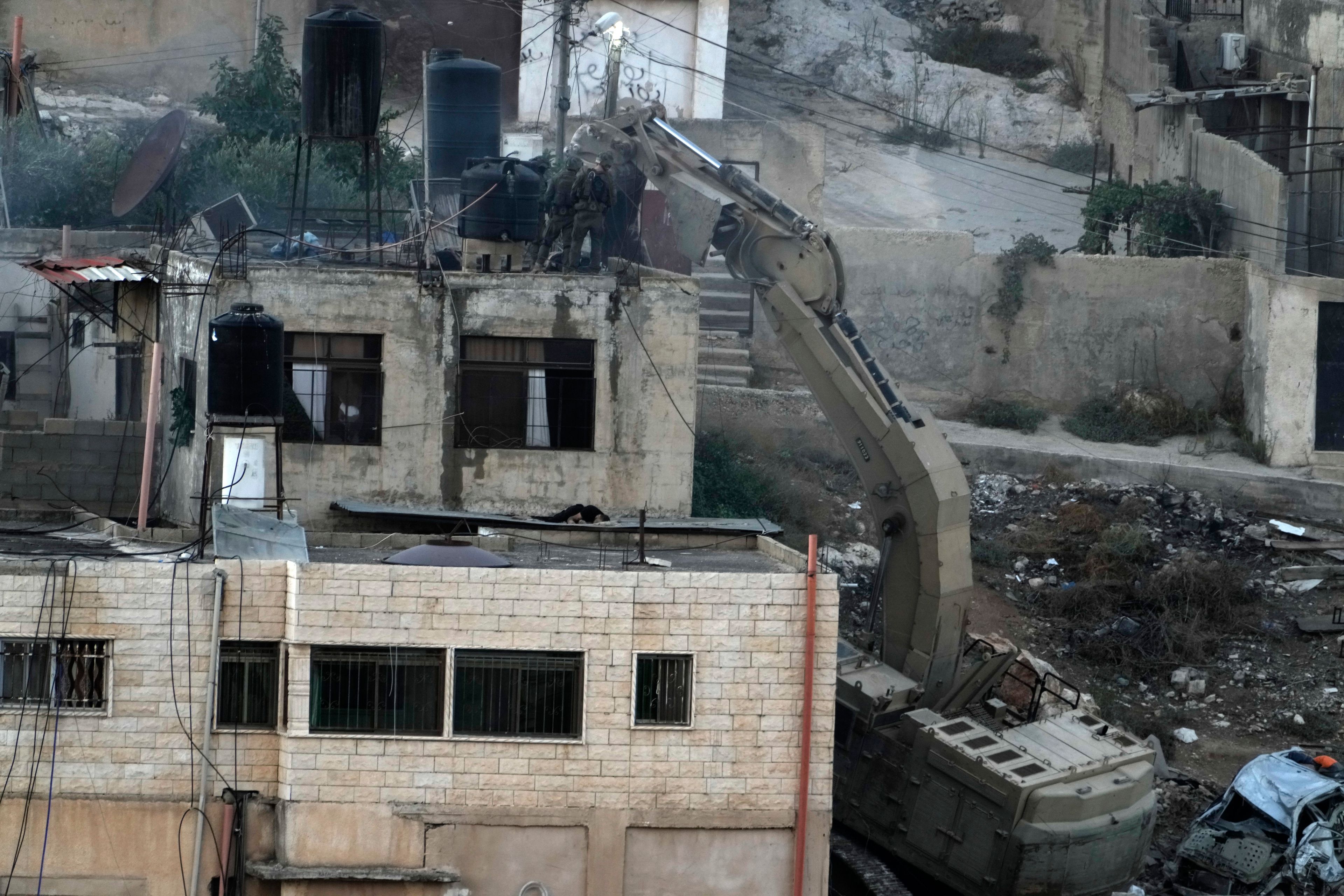 EDS NOTE: GRAPHIC CONTENT - Israeli soldiers look over a rooftop where two bodies lie motionless in the West Bank town of Qabatiya during a raid, Thursday, Sept. 19, 2024. (AP Photo/Majdi Mohammed)