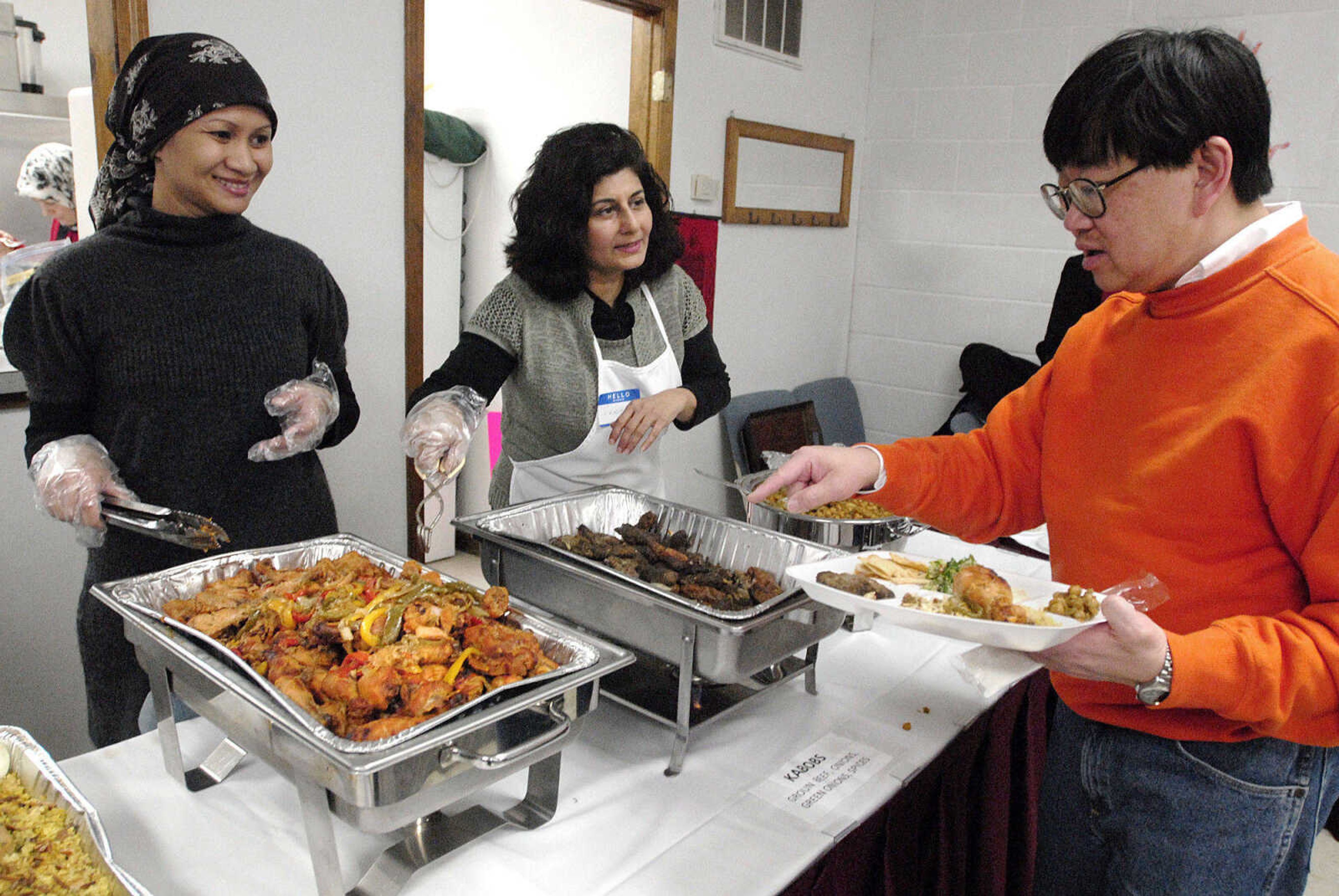 LAURA SIMON~lsimon@semissourian.com
Dr. Wilfred Lee asks two members of Cape Girardeau's Islamic Center, Laili Hudaifah, left, and Seemi Ahmed about the food they are serving during the center's Haiti benefit dinner.