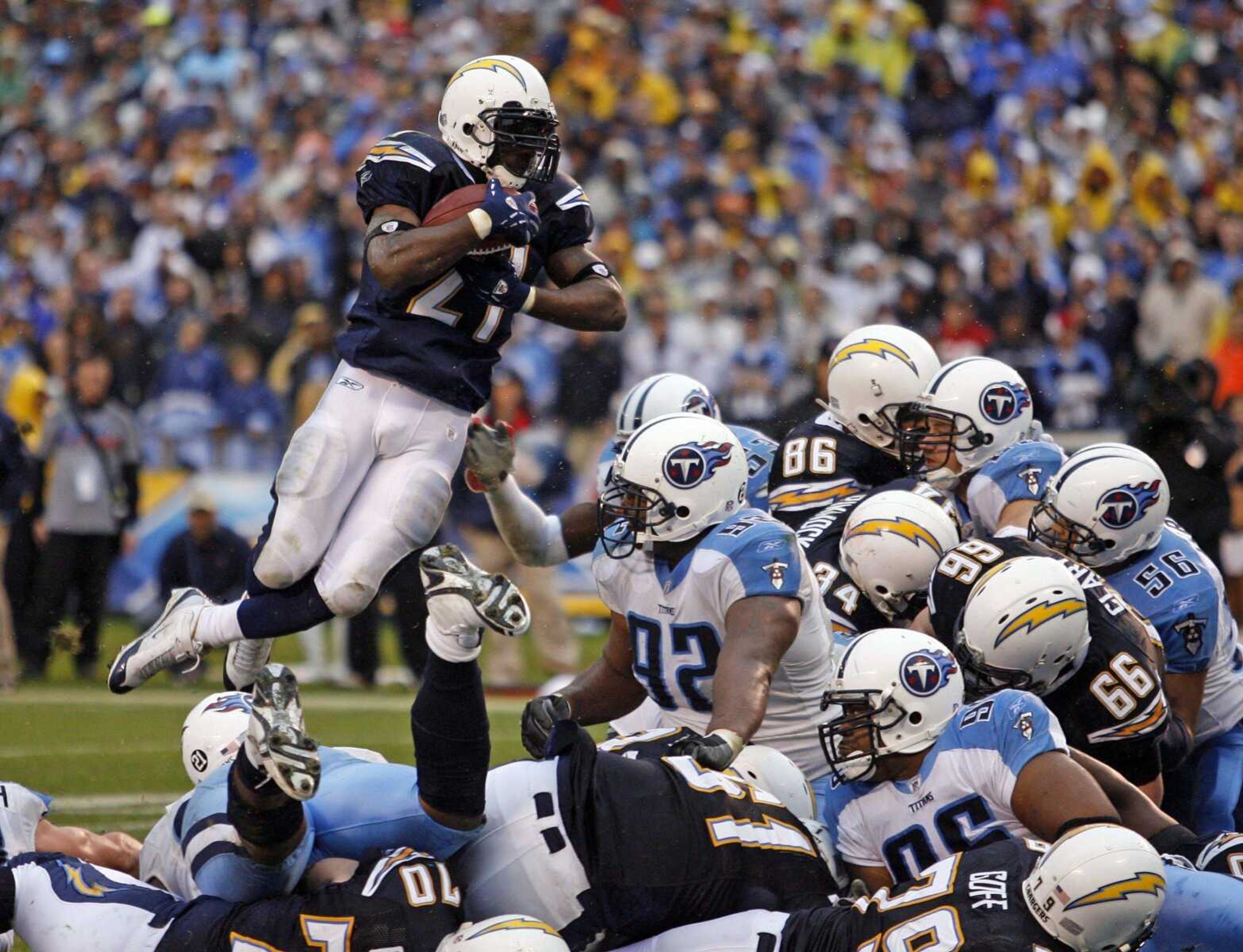 San Diego Chargers running back  LaDainian Tomlinson leaped over the Tennessee Titans defense as he scored on a 1-yard touchdown run  during the fourth quarter of their AFC wild-card playoff game Sunday in San Diego. (DENIS POROY ~ Associated Press)