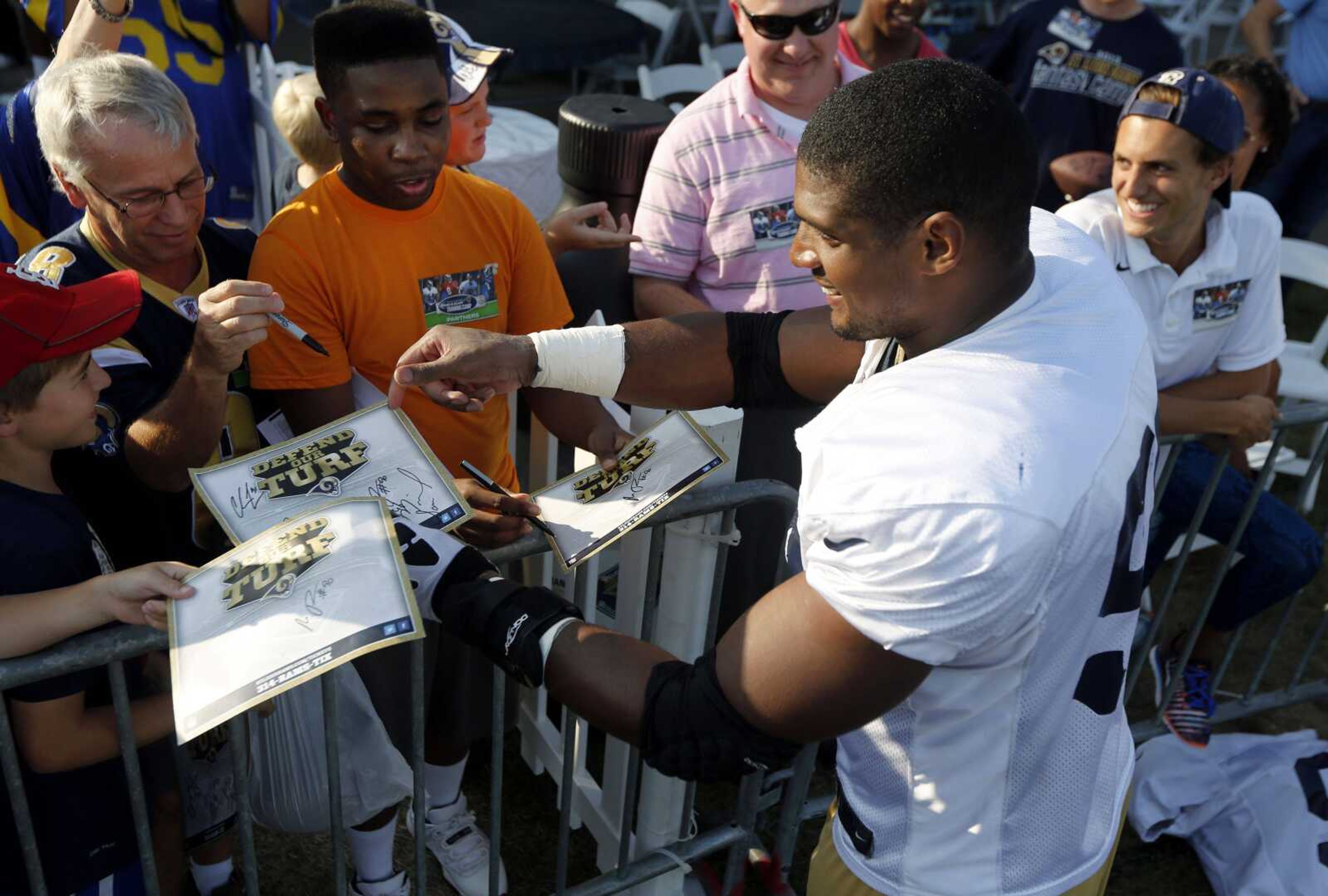 St. Louis Rams defensive end Michael Sam signs autographs for fans following practice at the NFL football team's training camp facility Tuesday, July 29, 2014, in St. Louis. (AP Photo/Jeff Roberson)