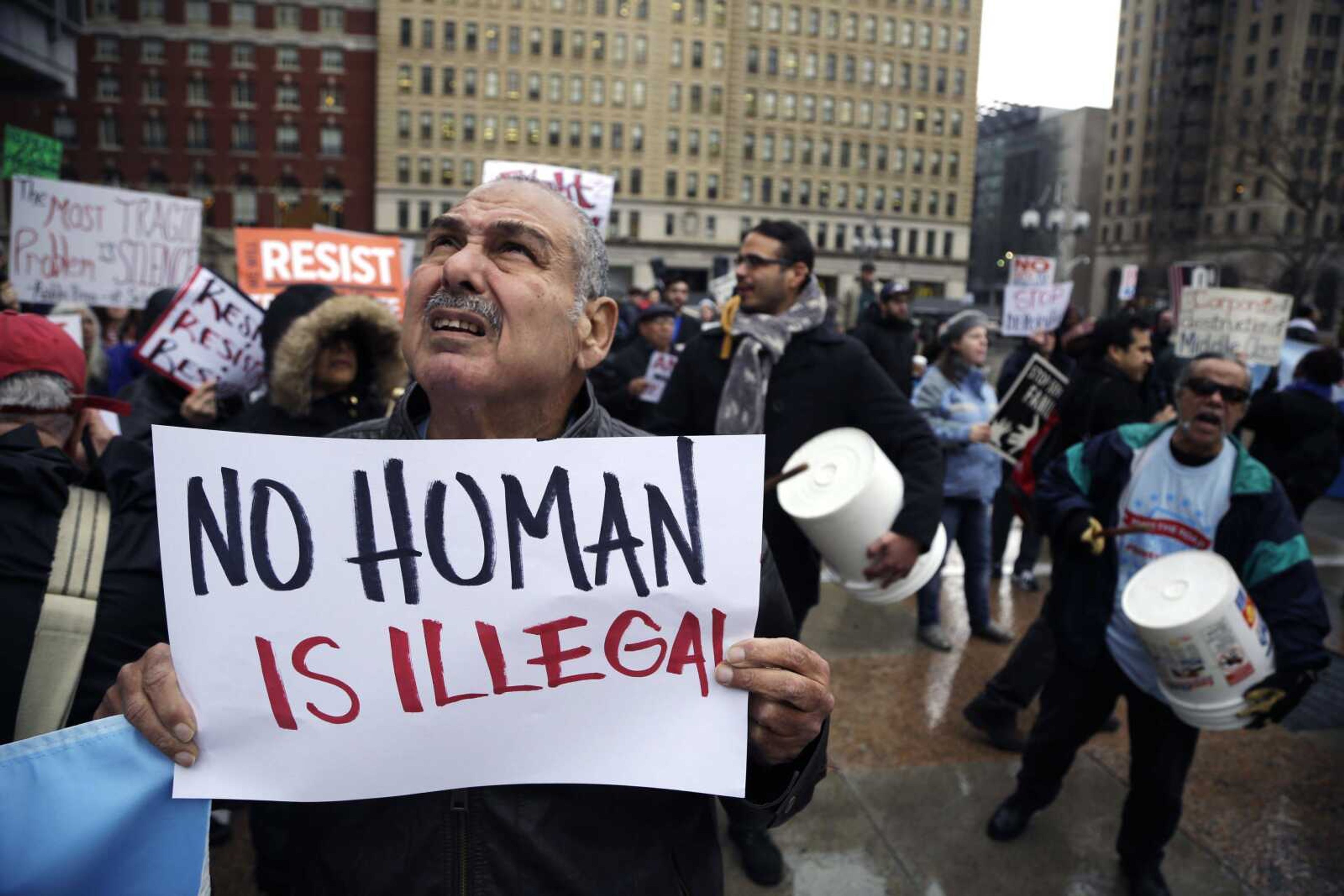 A protester looks toward a circling helicopter as he demonstrates against President Donald Trump's visit Thursday in Philadelphia. Trump traveled to Philadelphia to speak to House and Senate GOP lawmakers at their annual policy retreat.