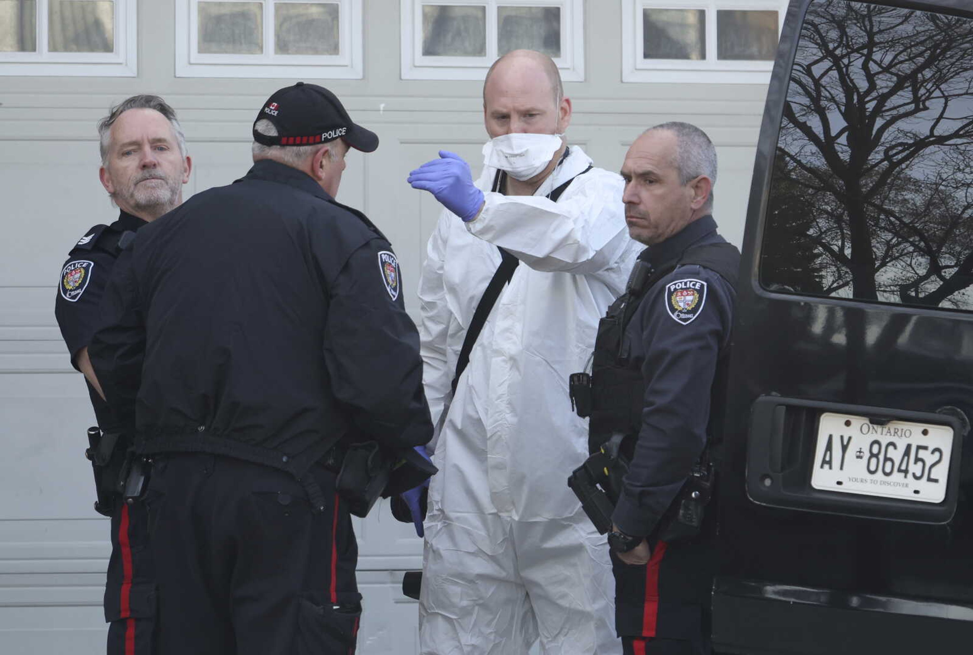 Police officers and a member of the coroner's office gather at the scene of a homicide where six people were found dead in the Barrhaven suburb of Ottawa on Thursday, March 7, 2024. (Patrick Doyle /The Canadian Press via AP)