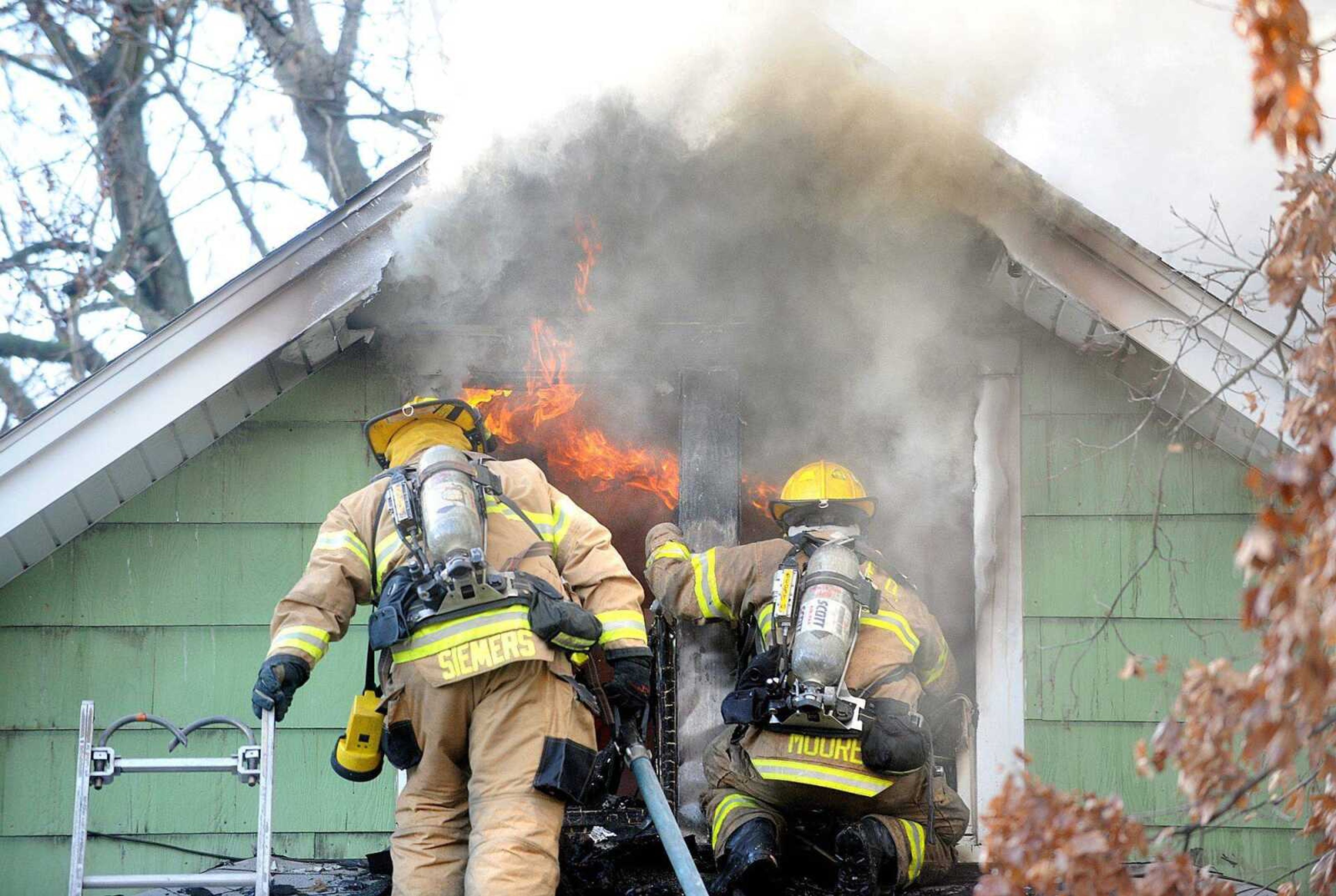 Firefighters Justin Siemers, left, and Nick Moore of the Cape Girardeau Fire Department access the scene of a fire inside the second story of a house at 801 S. Benton St. on Monday in Cape Girardeau. Nobody was injured in the fire. (Laura Simon)