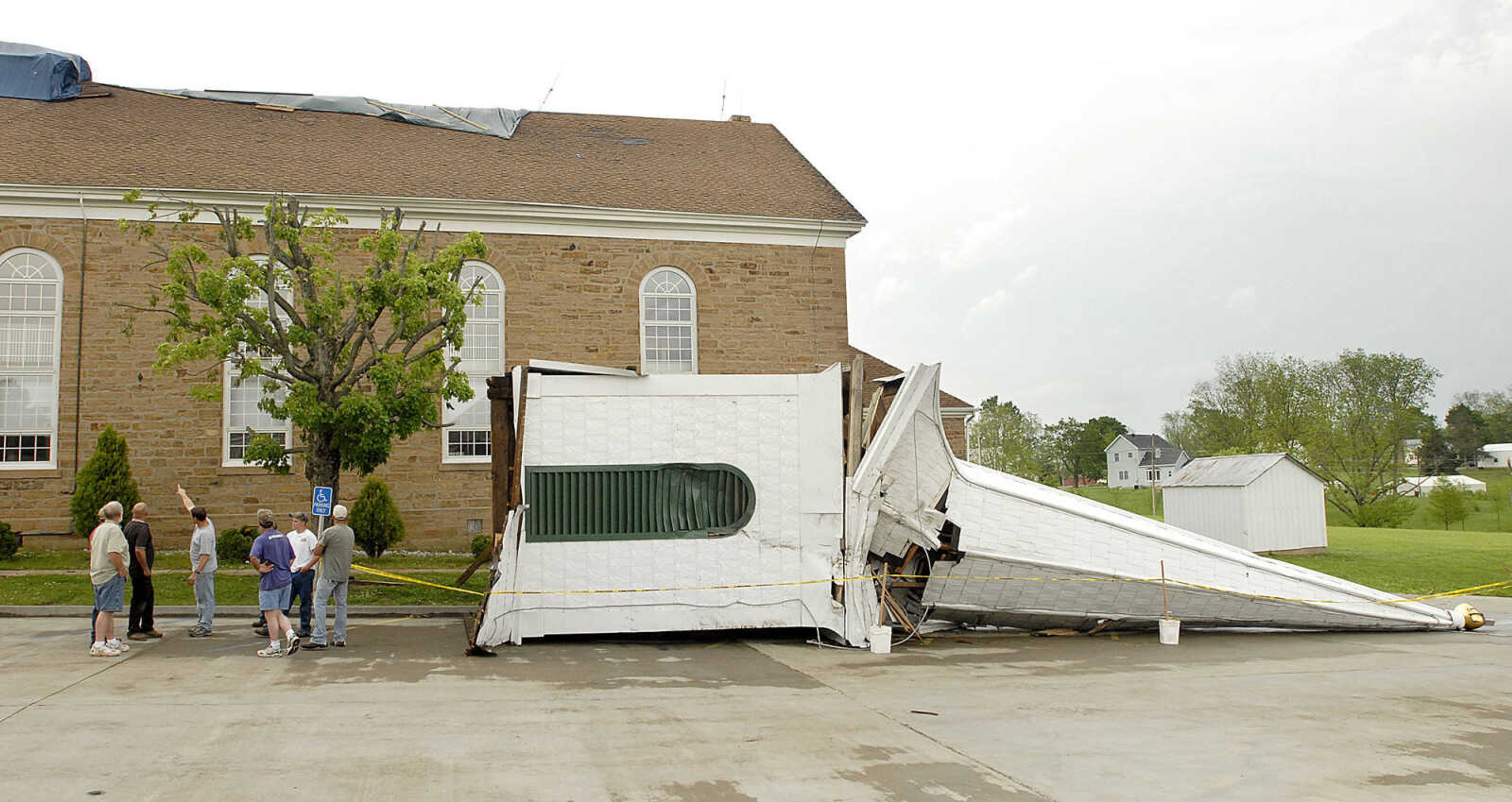 ELIZABETH DODD ~ edodd@semissourian.com
Members of Trinity Lutheran Church in Altenburg discuss plans for dealing with the damage Wednesday from May 8 storms next to the old steeple that had to be removed from the roof after blowing over.