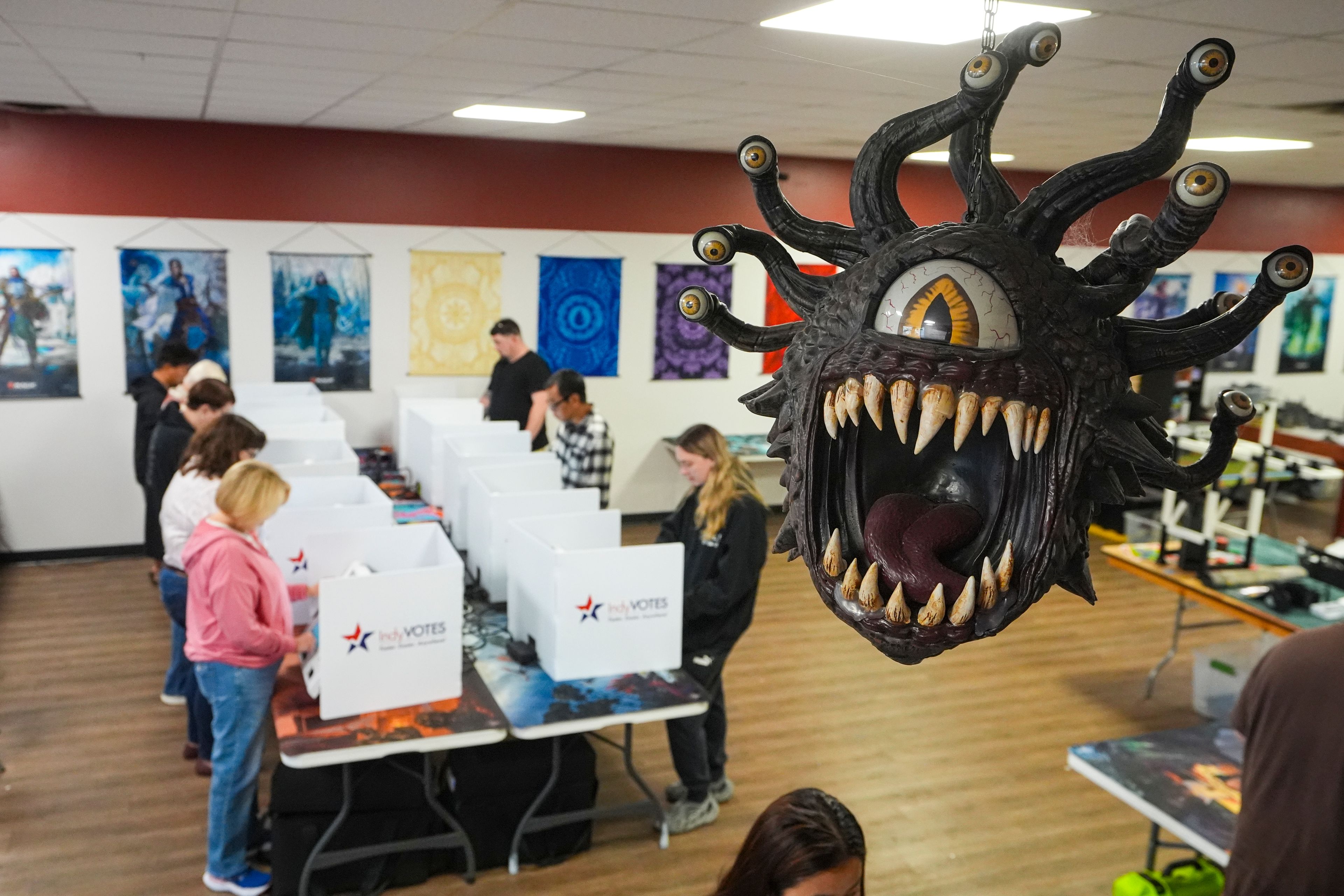 Beholder, a fictional monster in the Dungeons & Dragons fantasy role-playing game, hangs over a voting site as voter cast their ballots on Election Day, at The Game Preserve store in Indianapolis, Tuesday, Nov. 5, 2024. (AP Photo/Michael Conroy)