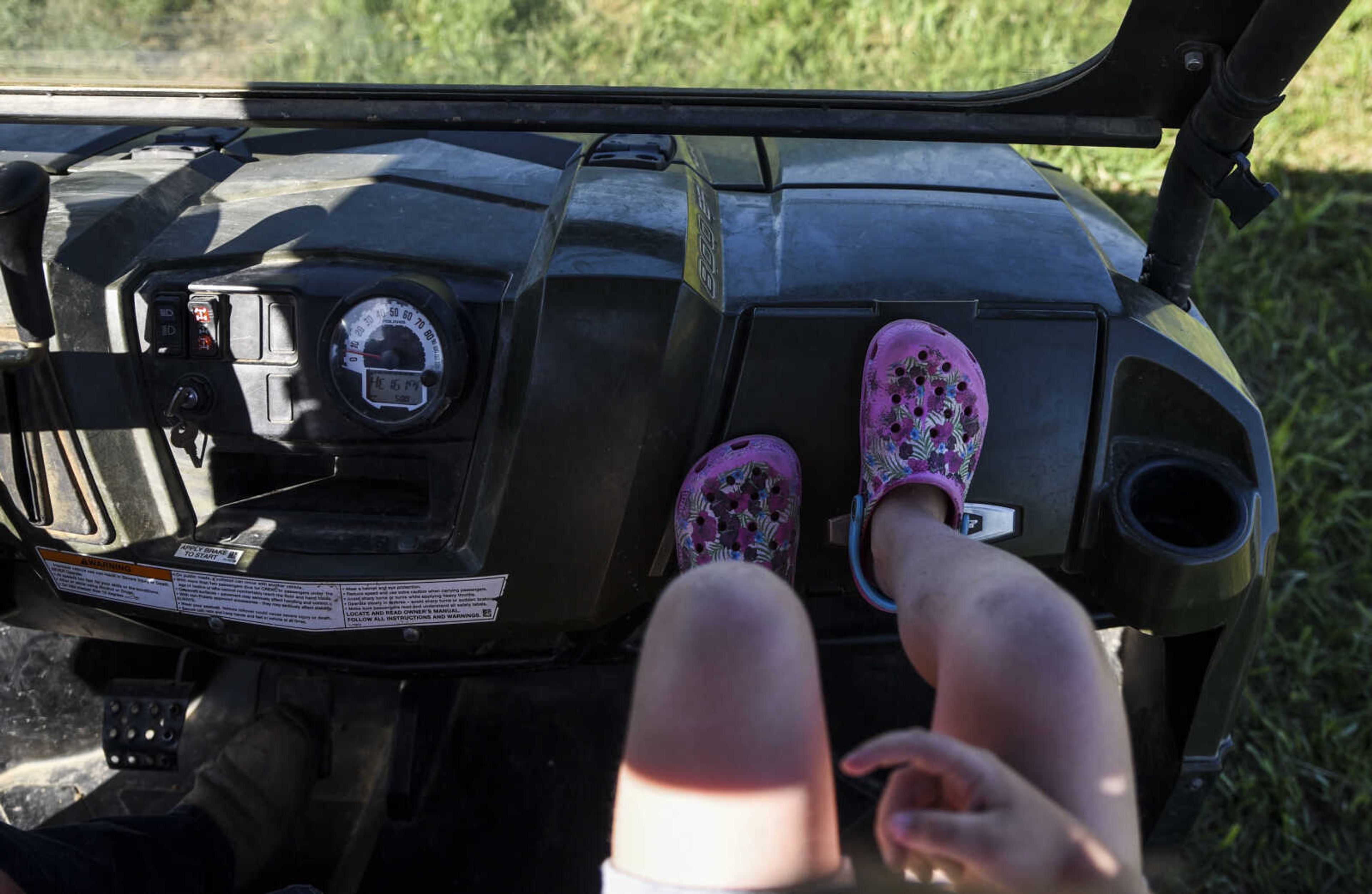 Lindyn Davenport puts her feet up on the dashboard of her family's ATV while riding out to the pasture to feed their cows on their farm Sunday, June 3, 2018 in Sedgewickville.