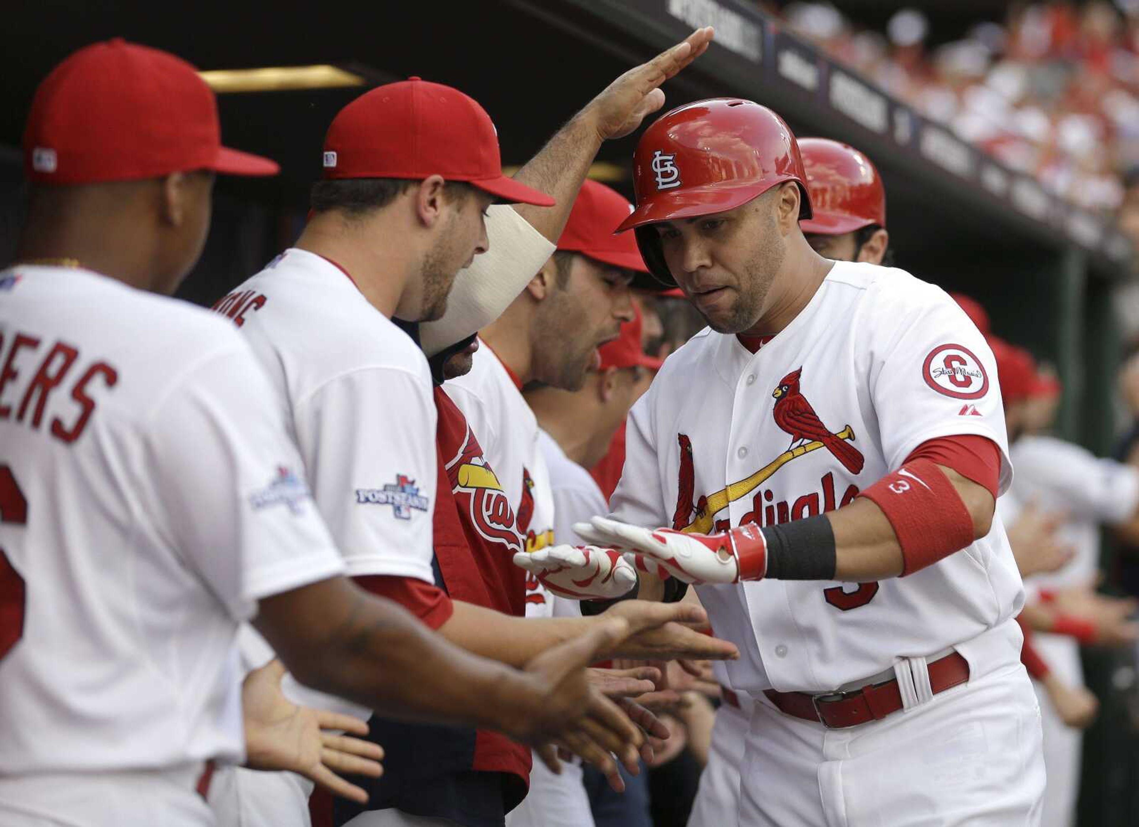 St. Louis Cardinals' Carlos Beltran, right, is congratulated in the dugout by teammates after hitting a three-run home run against the Pittsburgh Pirates in the third inning of Game 1 of baseball's National League division series on Thursday, Oct. 3, 2013, in St. Louis. (AP Photo/Jeff Roberson)