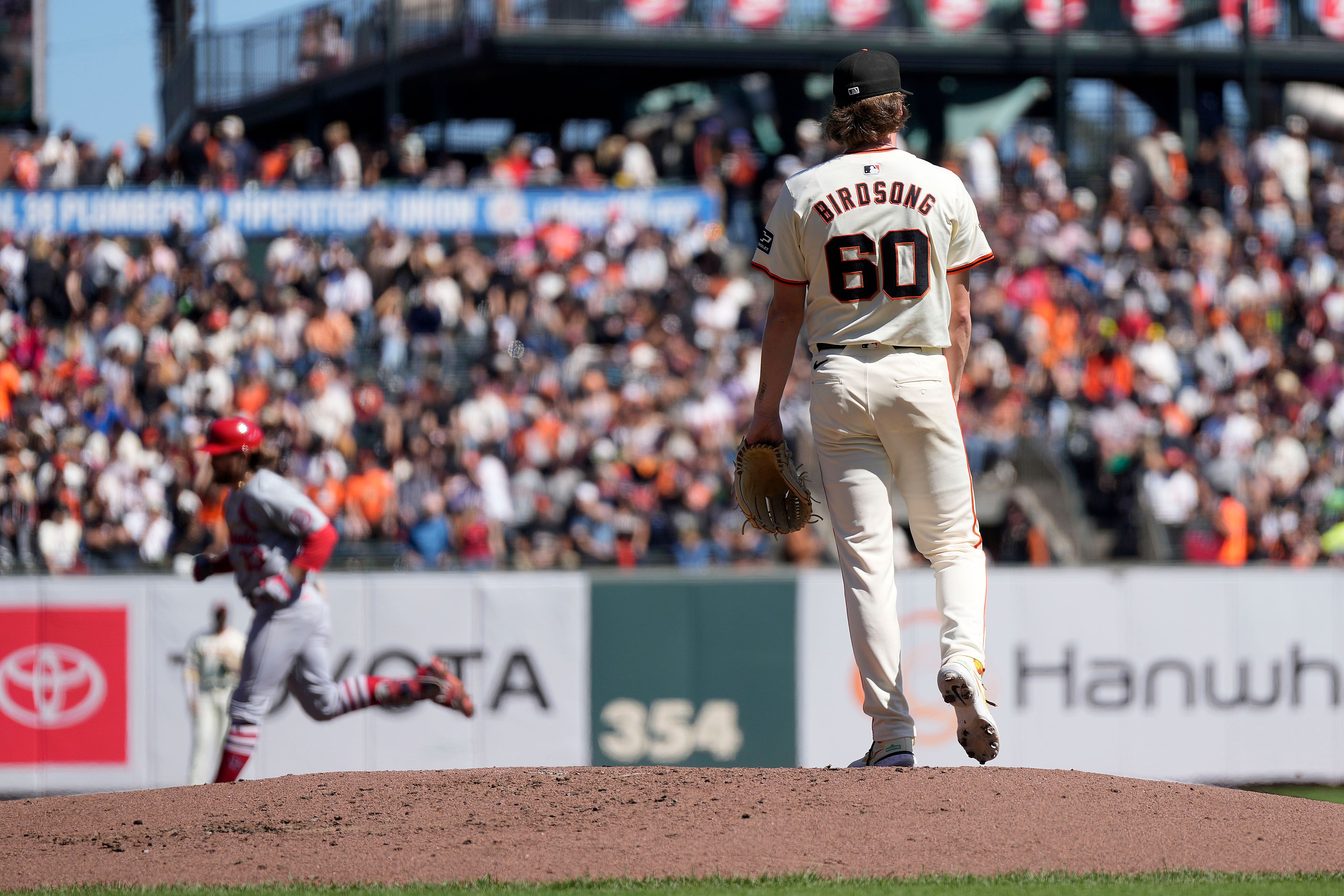 San Francisco Giants pitcher Hayden Birdsong (60) stands on the mound as St. Louis Cardinals' Brendan Donovan, back left, rounds the bases after hitting a solo home during the third inning of a baseball game Sunday, Sept. 29, 2024, in San Francisco. (AP Photo/Tony Avelar)