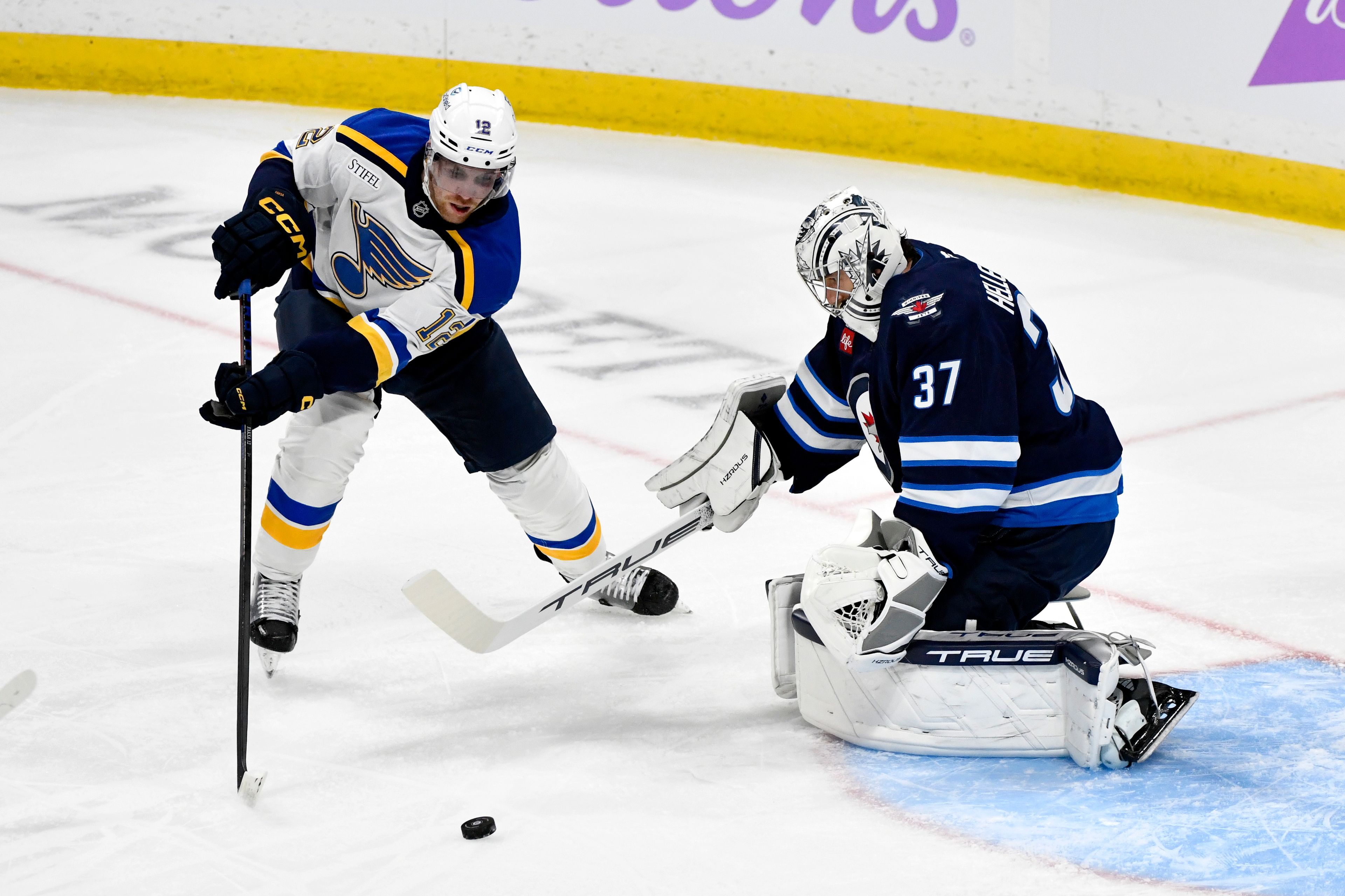 Winnipeg Jets goaltender Connor Hellebuyck (37) makes a save on St. Louis Blues' Radek Faksa (12) during the first period of their NHL hockey game in Winnipeg, Tuesday Dec. 3, 2024. (Fred Greenslade/The Canadian Press via AP)