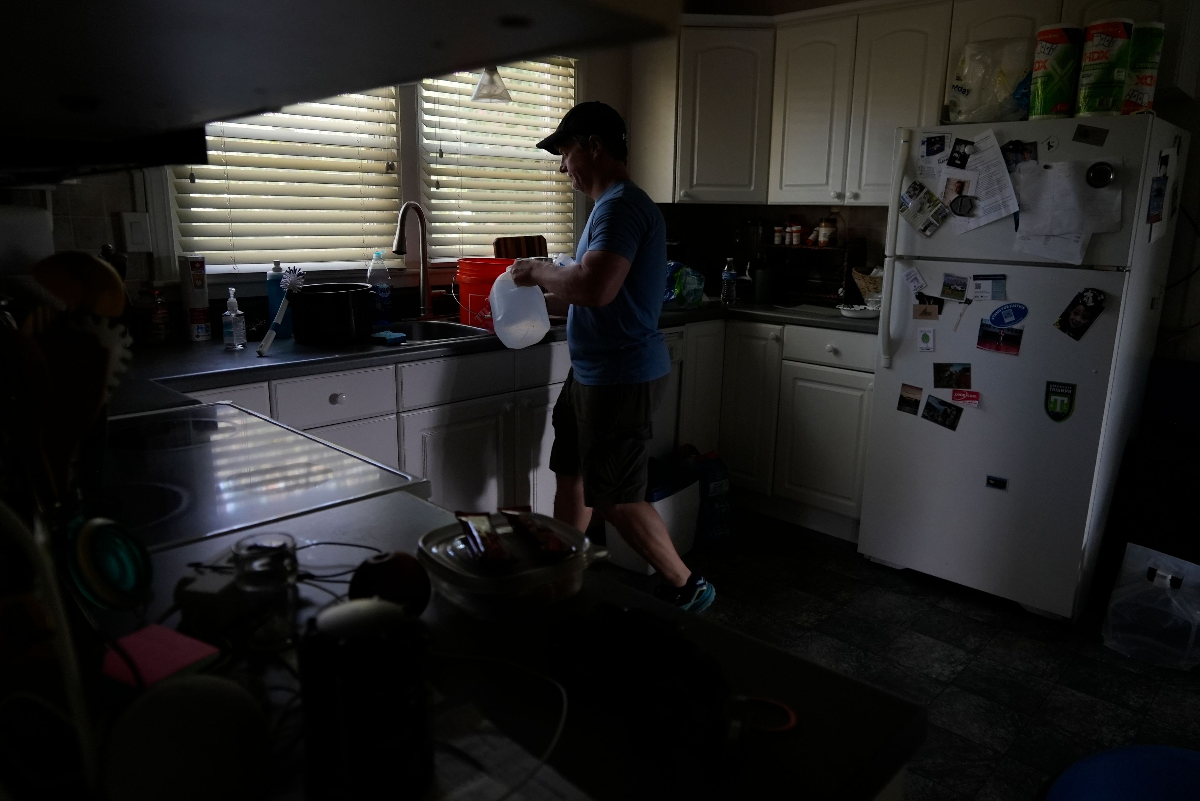 Travis Edwards organizes his drinking water supply Thursday, Oct. 3, 2024 in Asheville, North Carolina. He hasn't had water since Hurricane Helene struck the area, and reuses water to flush toilets. (AP Photo/Brittany Peterson)