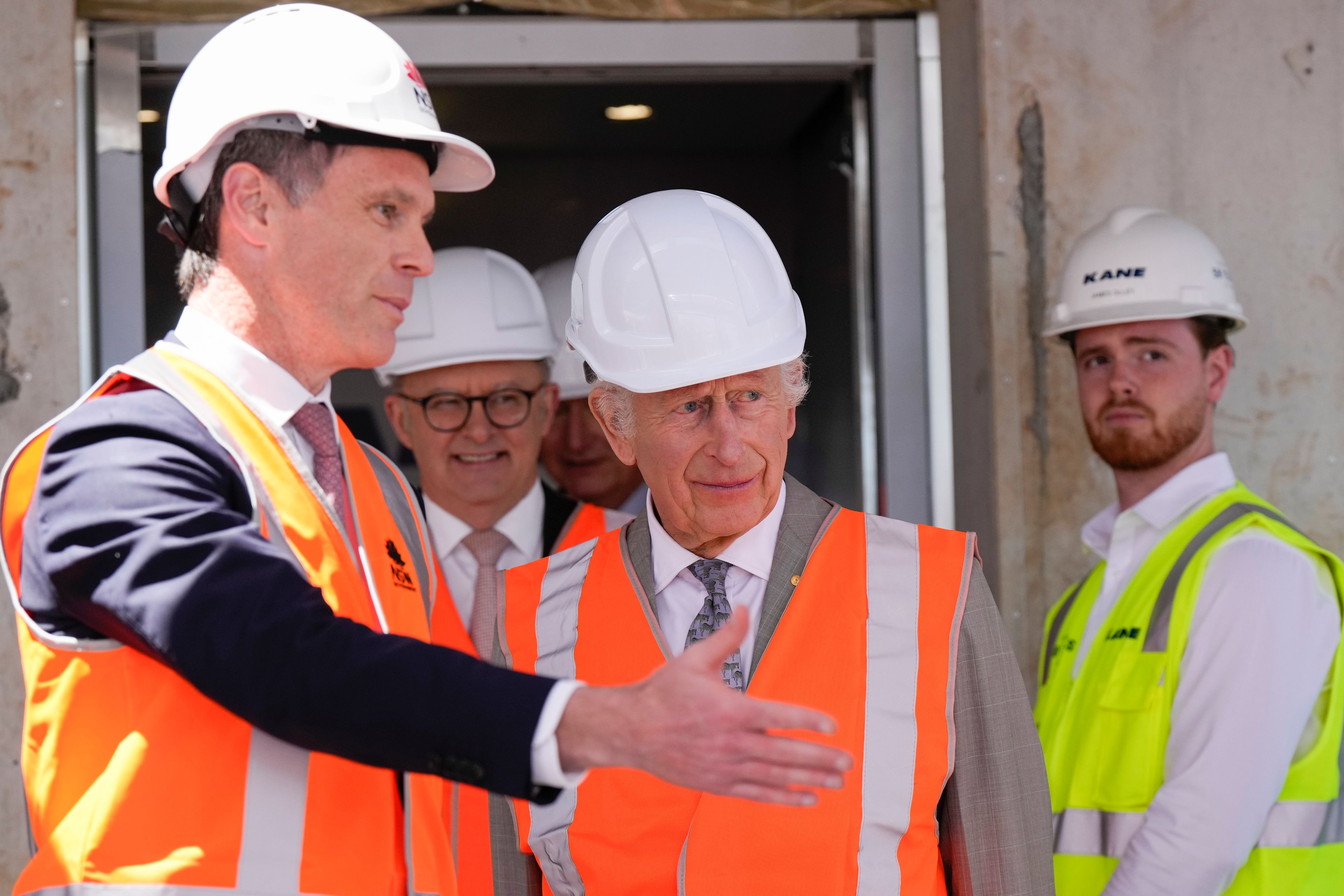 Britain's King Charles III, center, is assisted by New South Wales Premier Chris Minns, left, while Australia's Prime Minister Anthony Albanese walks behind during his visit at the Homes NSW Cowper Street development in Sydney, Australia, Tuesday, Oct. 22, 2024. (AP Photo/Mark Baker, Pool)