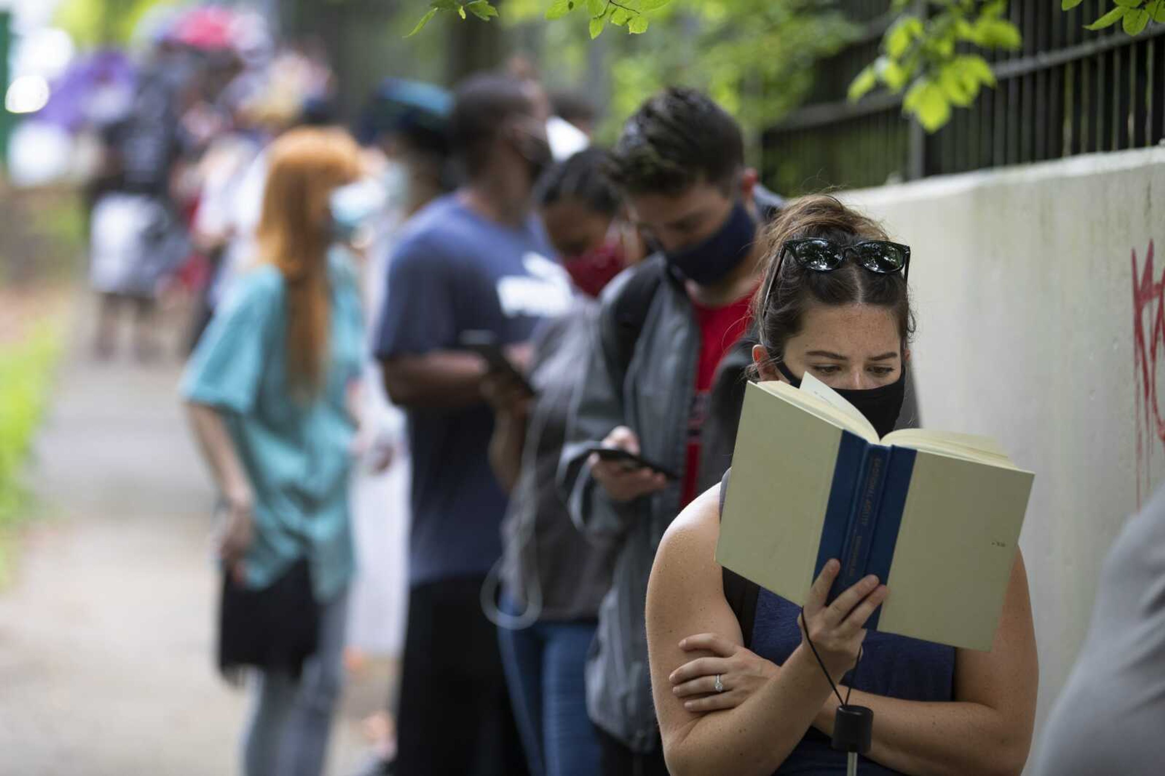 Kelsey Luker reads as she waits in line to vote Tuesday in Atlanta. Luker said she had been in line for almost two hours.