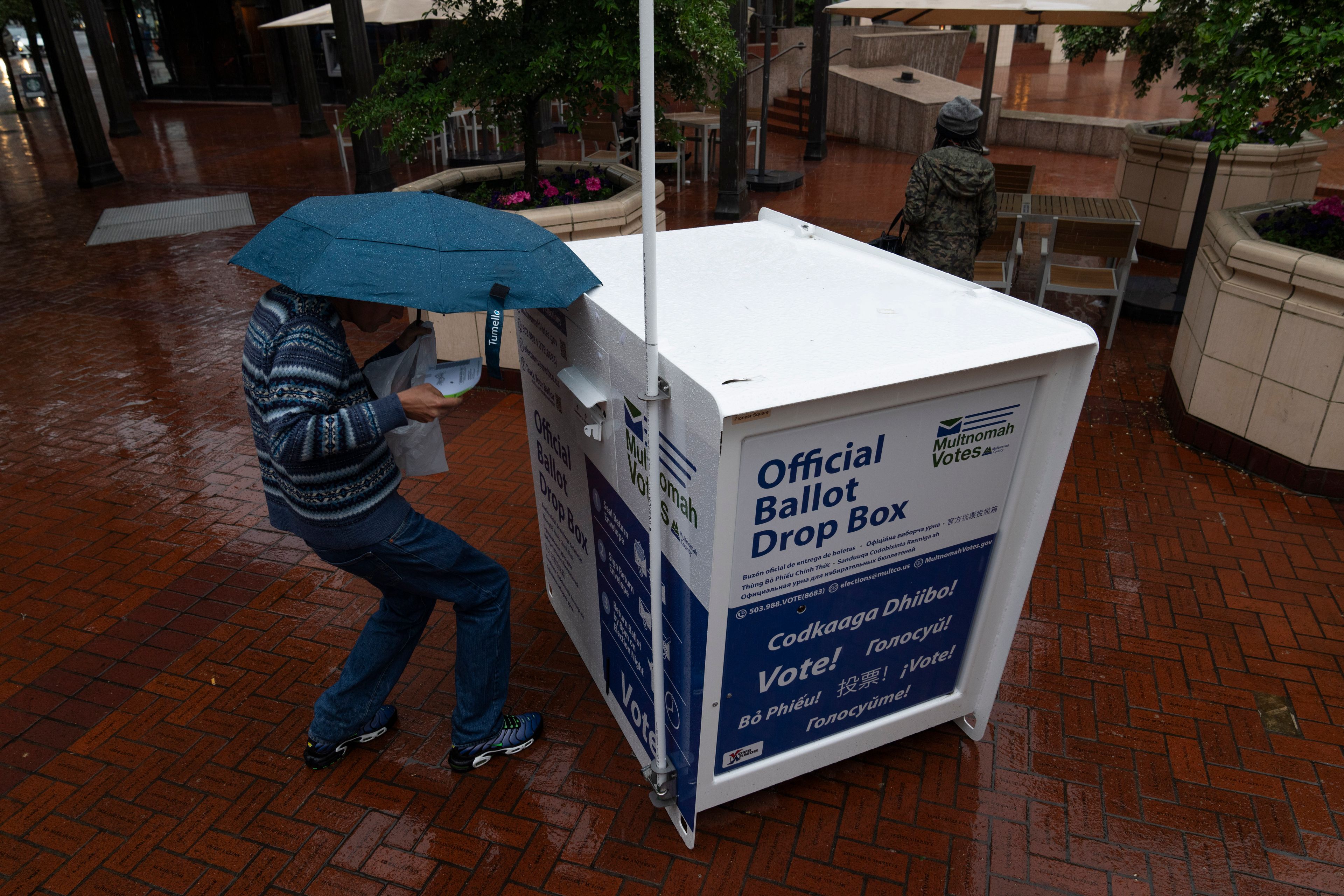 FILE - A person drops off their vote-by-mail ballot at a dropbox in Pioneer Square during primary voting on Tuesday, May 21, 2024, in Portland, Ore. (AP Photo/Jenny Kane, File)