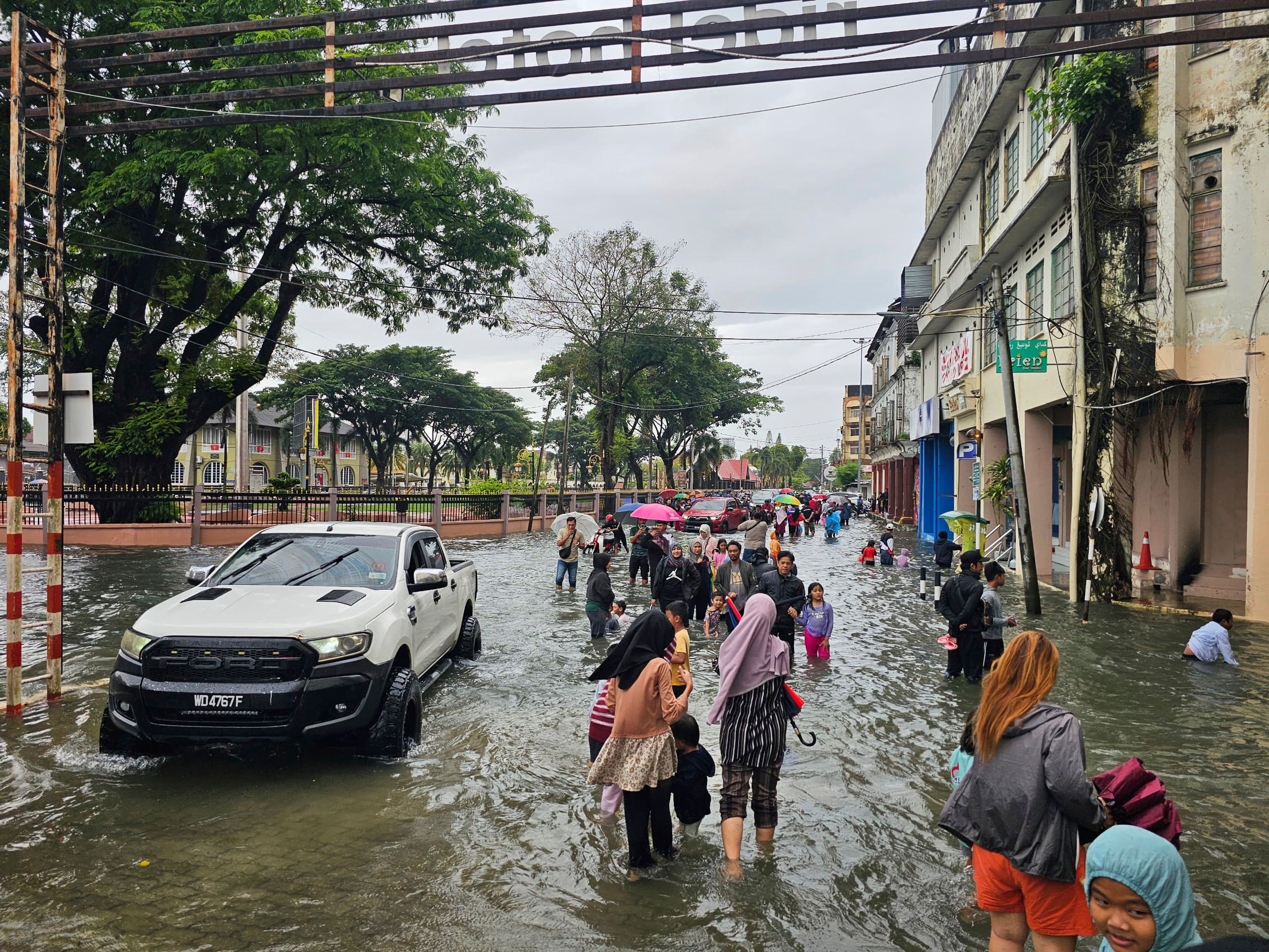 Residents walk on a flooded street after heavy monsoon rains in downtown Kota Bharu, Kelantan, Malaysia, Friday, Nov. 29, 2024. (AP Photo/Loo Kok Chong)