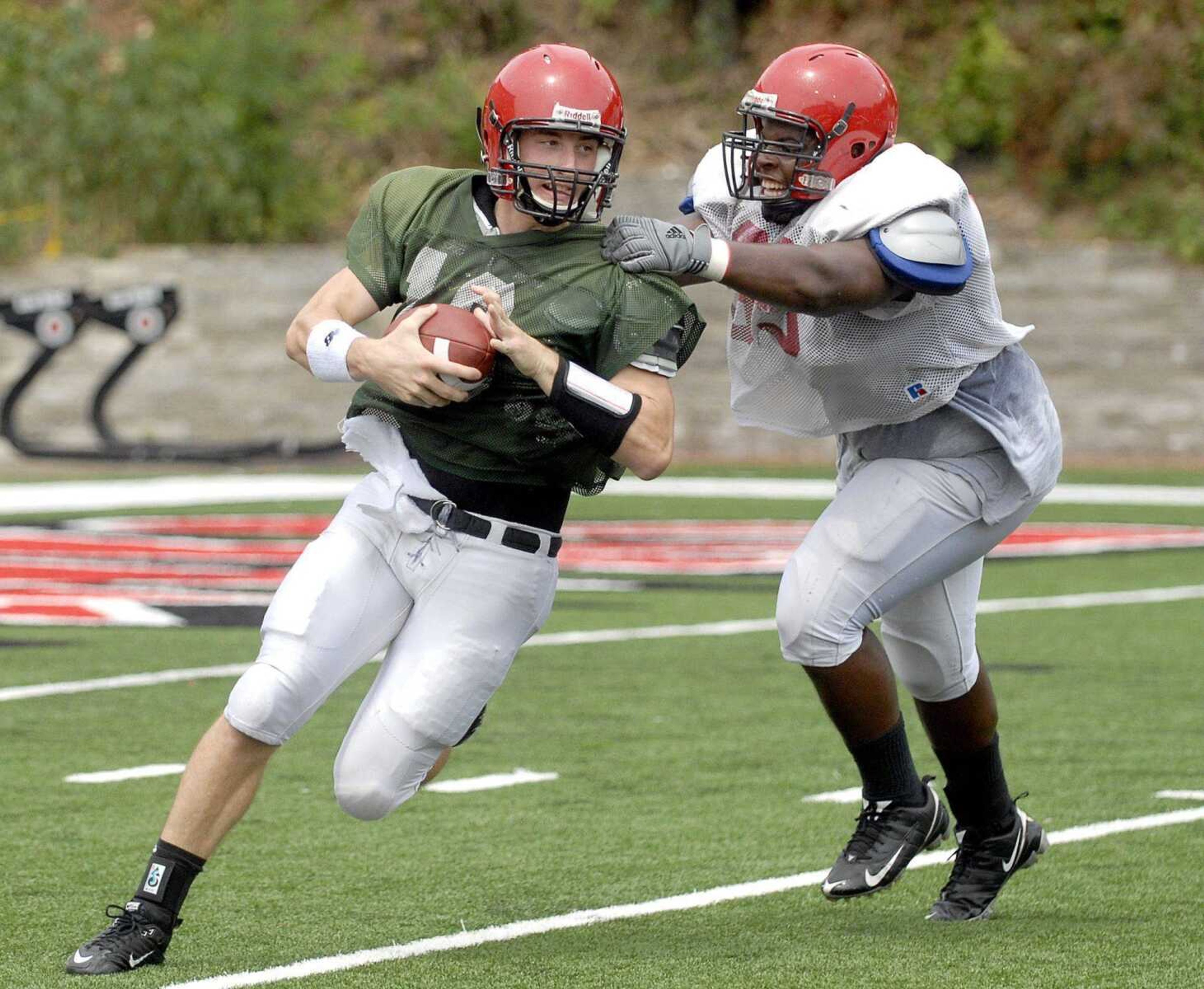 ABOVE: Southeast Missouri State quarterback Matt Scheible is confronted by defensive tackle Quinn Perry during Saturday's scrimmage at Houck Stadium. TOP: Southeast Missouri State coach Tony Samuel shares a lighter moment along the sideline during the scrimmage. (Laura Simon)