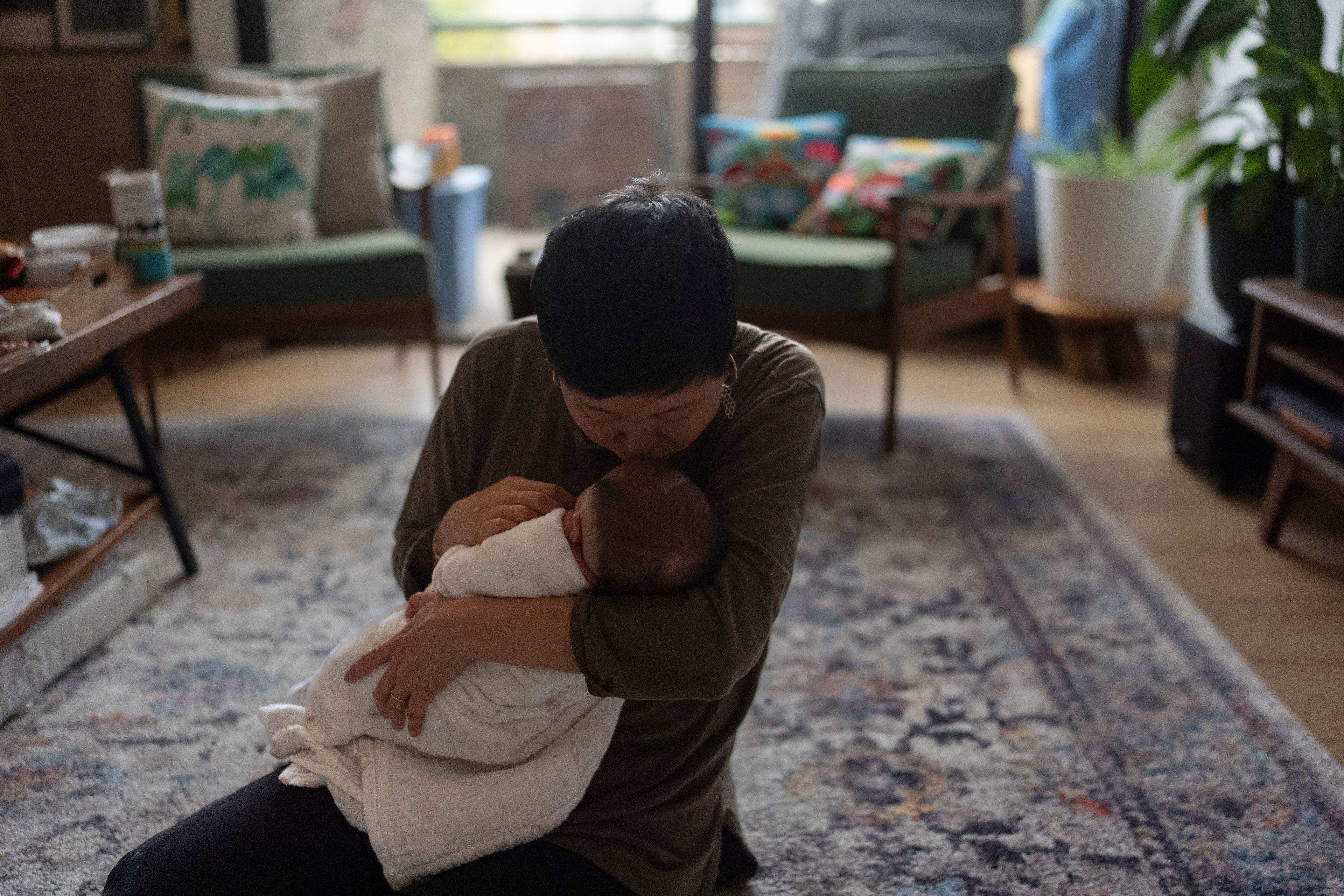 Robyn Joy Park, an adoptee from South Korea, kisses her newborn daughter, Rae, on the forehead at her home in Pasadena, Calif., Friday, April 19, 2024. (AP Photo/Jae C. Hong)