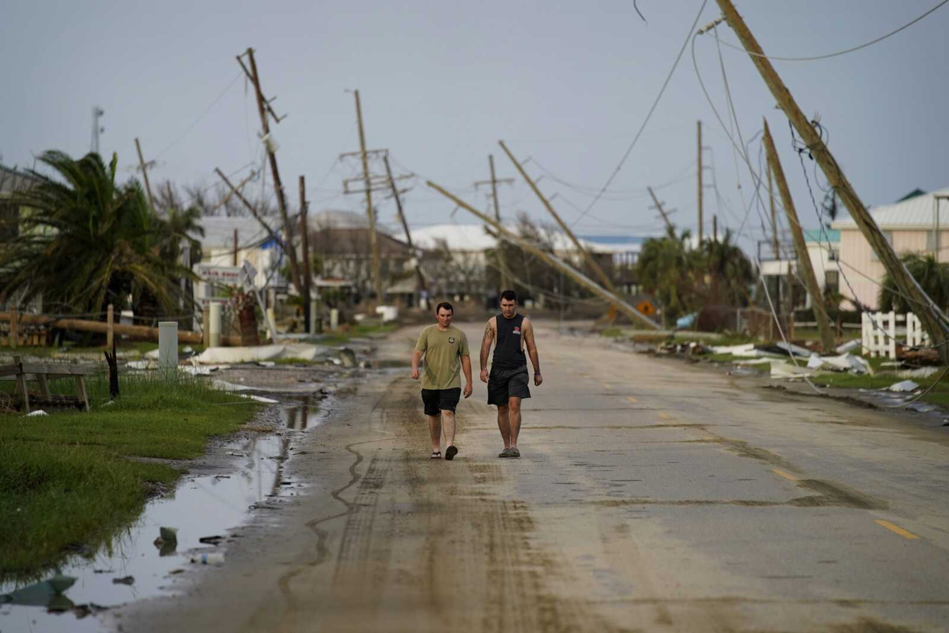 People walk through a neighborhood damaged by Hurricane Ida on Monday in Grand Isle, Louisiana.