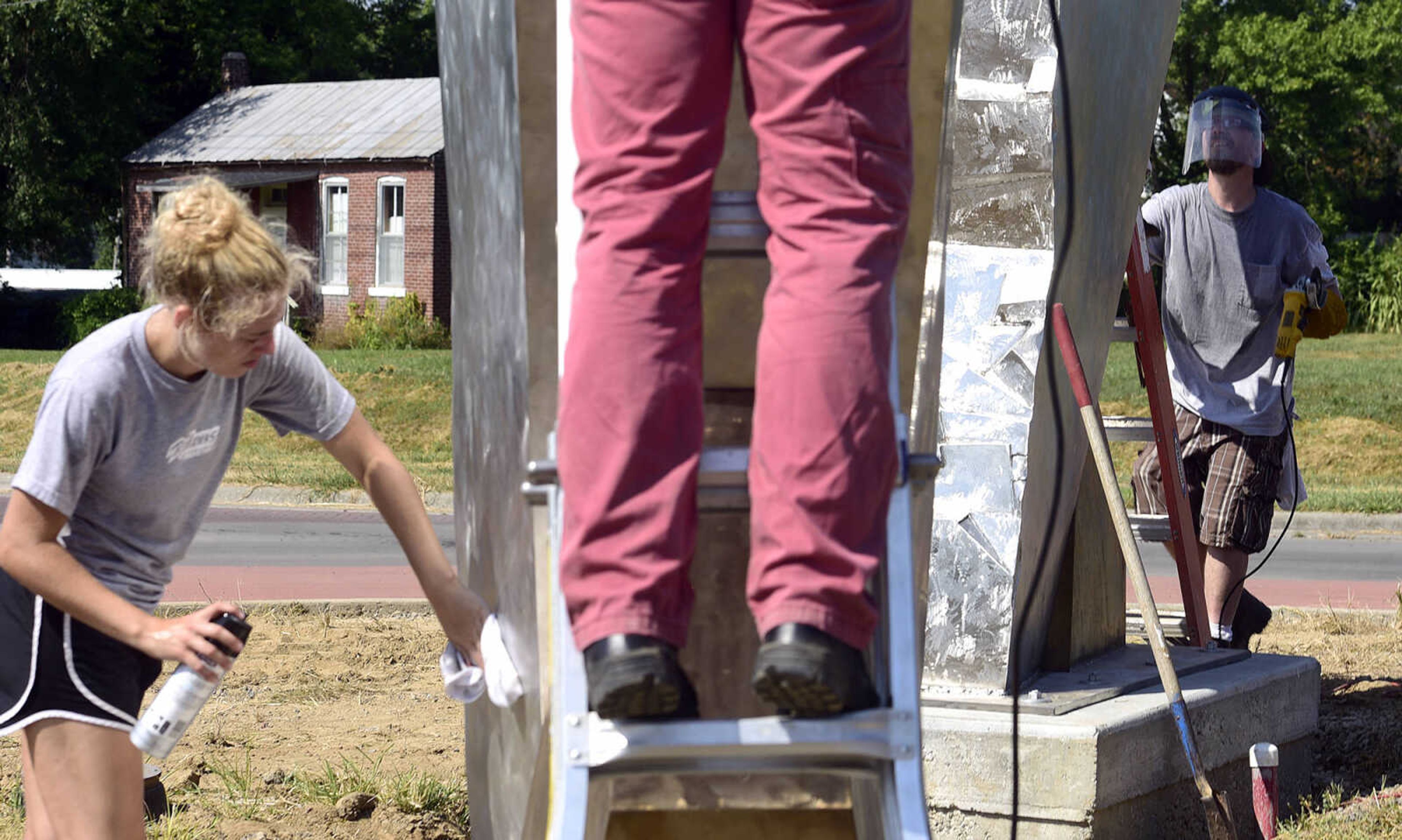 Jessica Lambert, left, Terry Davis, center, and Chris Wubbena clean up and polish Wubbena's sculpture, "Commence" after the installation of the 14-foot sculpture in the Fountain Street roundabout on Monday, July 24, 2017, near the River Campus in Cape Girardeau.