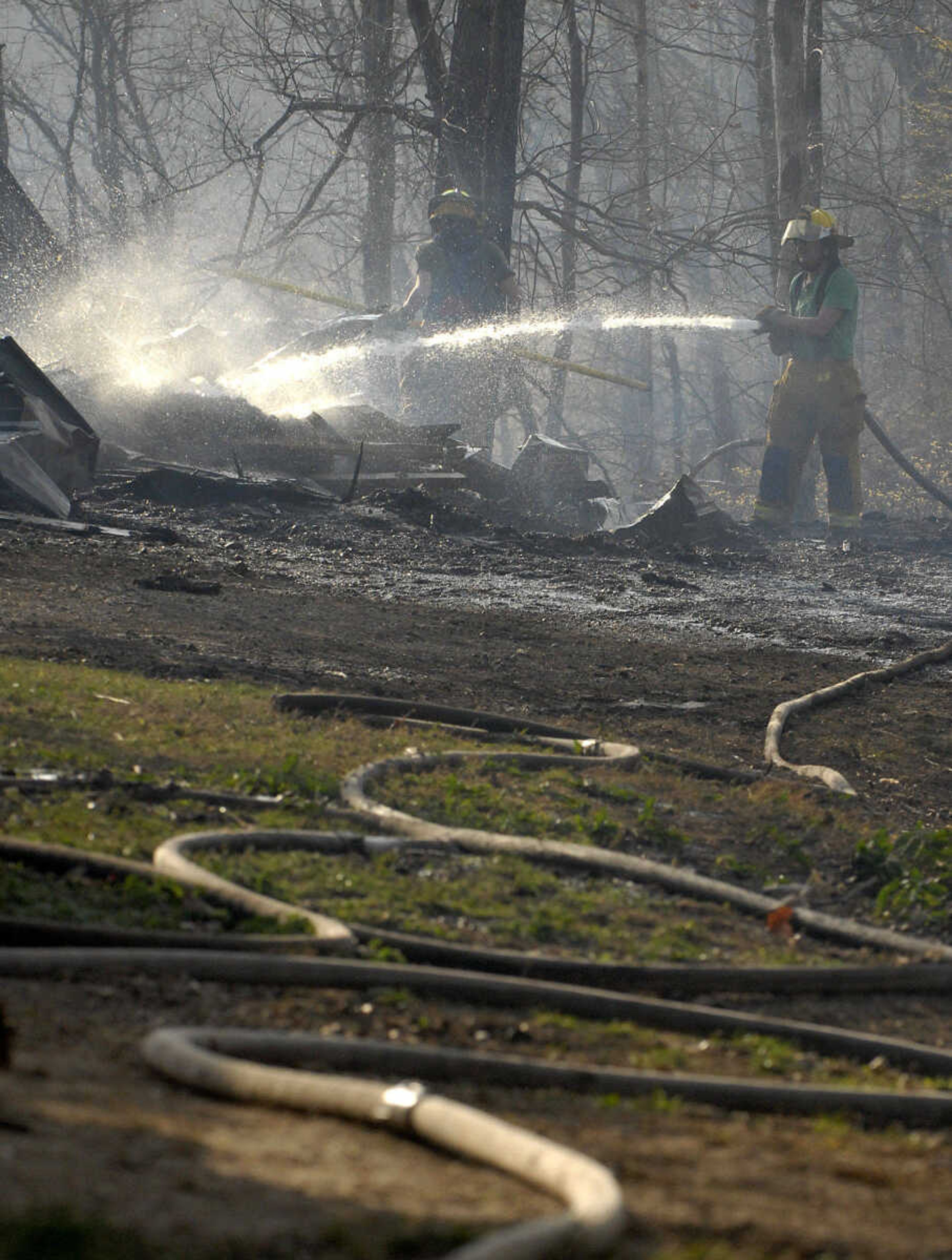 LAURA SIMON~lsimon@semissourian.com
Fire crews extinguish fire on the rubble of a shed that burned to the ground during a natural cover fire off of Cissus Lane in rural Cape Girardeau County Sunday, April 3, 2011. Firefighters from Cape Girardeau, Perry, Scott, and Bollinger Counties contained the blaze that ravaged 50 acres of land.