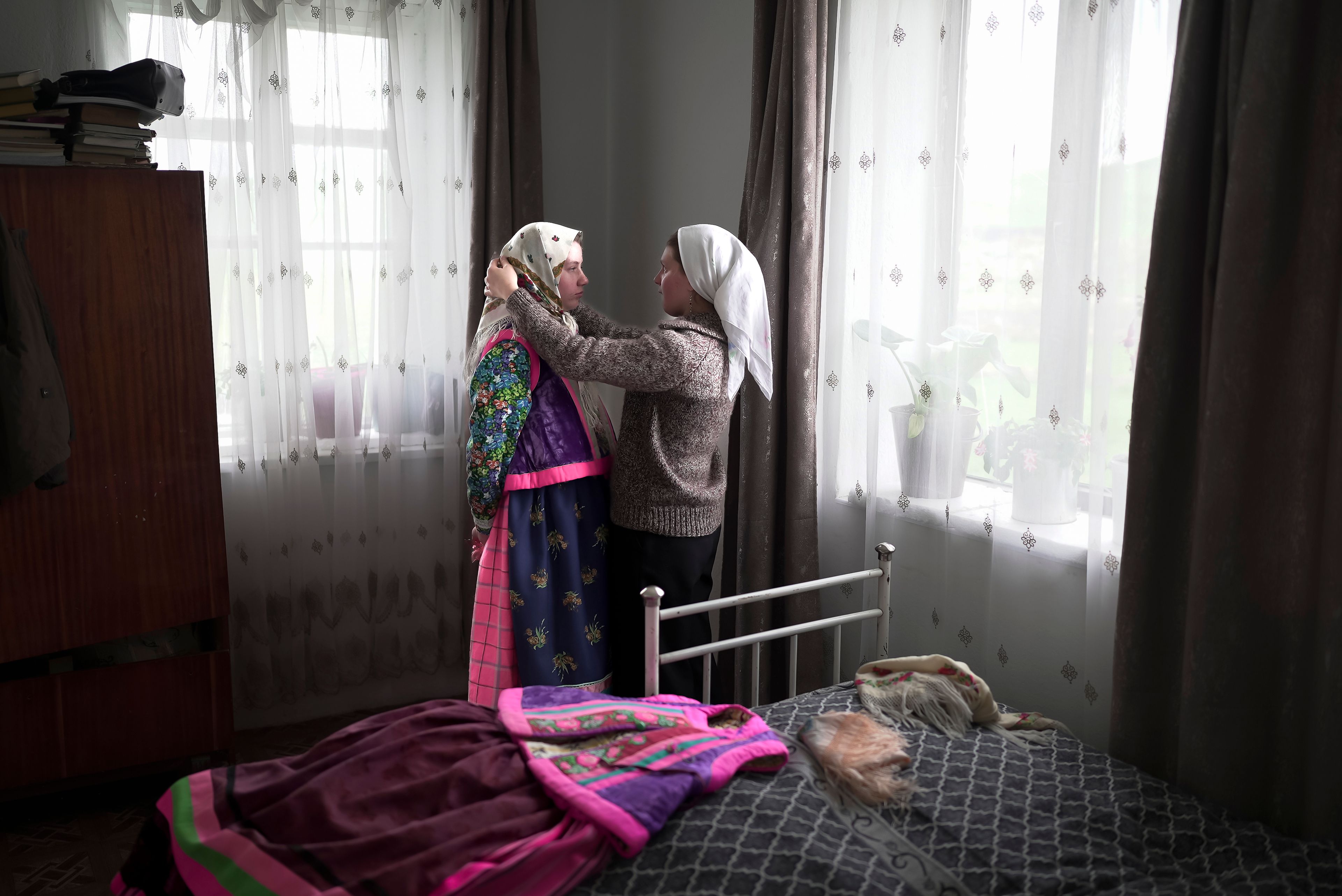 Daria Strukova, right, helps her sister Nina Strukova, left, put on a traditional Doukhobor dress in the remote mountain village of Orlovka, Georgia, Sunday, May 5, 2024. (AP Photo/Kostya Manenkov)