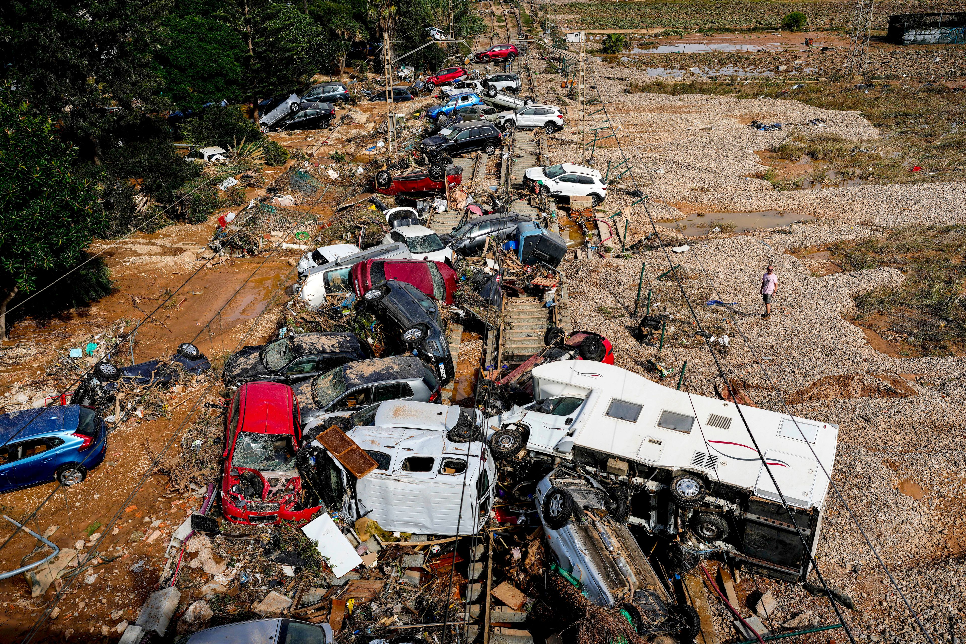 A man stands next to flooded cars piled up in Valencia, Spain, Thursday, Oct. 31, 2024. (AP Photo/Manu Fernandez)