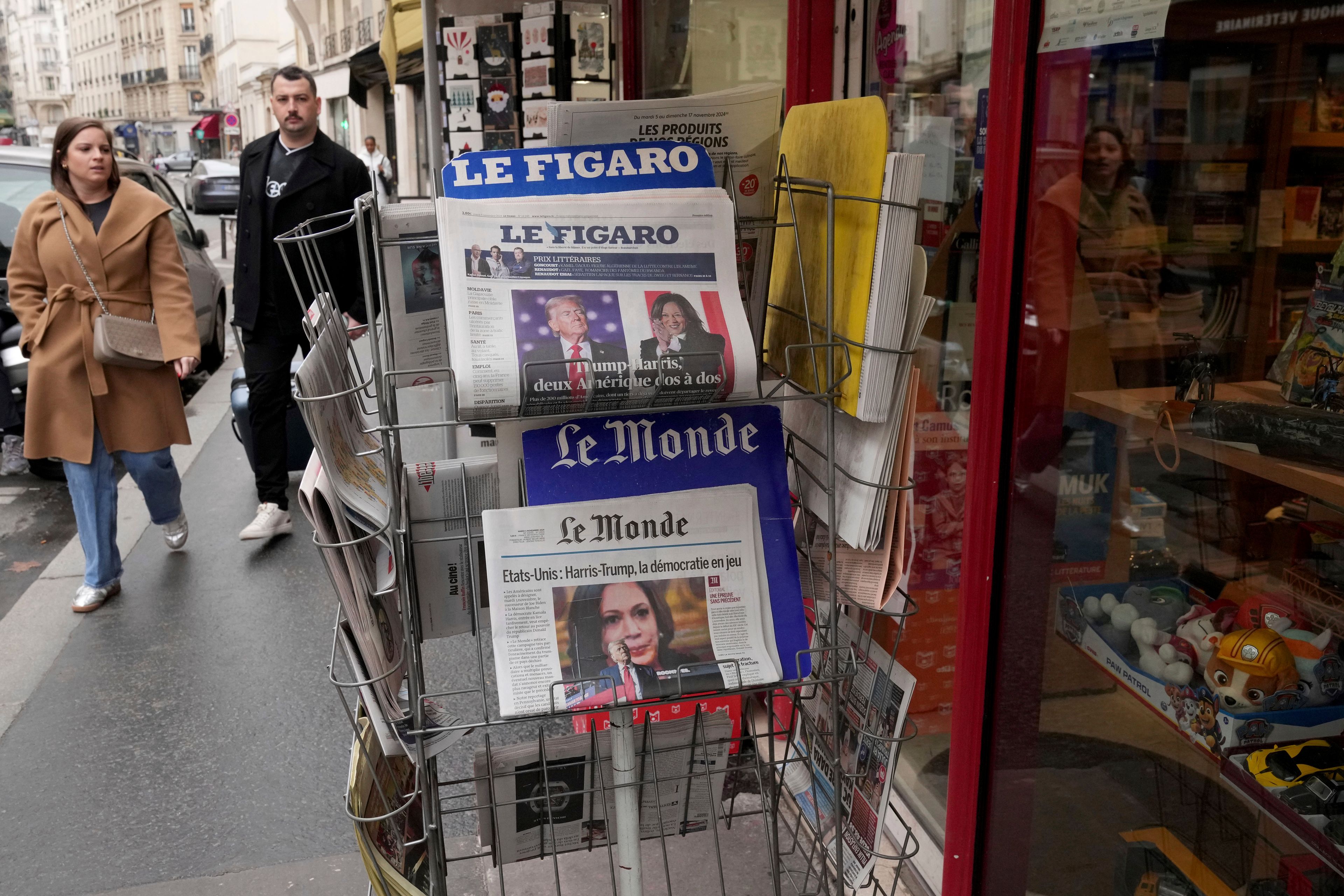 People walk past a newsstand with newspapers headlining on the US election, Tuesday, Nov. 5, 2024 in Paris. (AP Photo/Michel Euler)