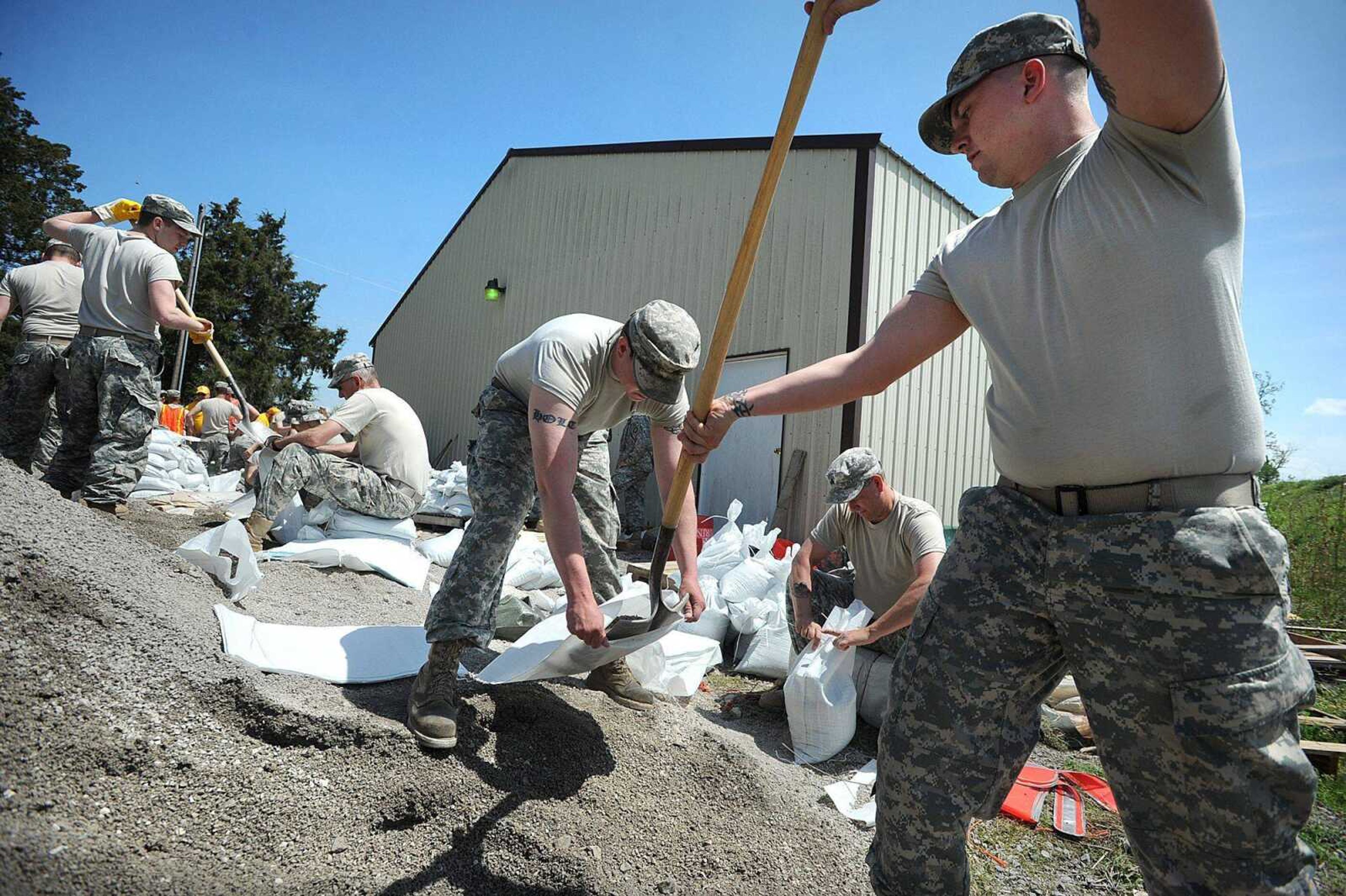 Missouri National Guard soldiers Jordan Barnhart, right and Jonathan Holt, left, and Jeff Smith, center, form an assembly line along with their fellow guardsmen to fill sandbags with chat rock Monday, April 22, 2013 in Dutchtown. Around 50 National Guard soldiers were expected in Dutchtown by Monday evening to help locals protect their property from the rising floodwaters. (Laura Simon)