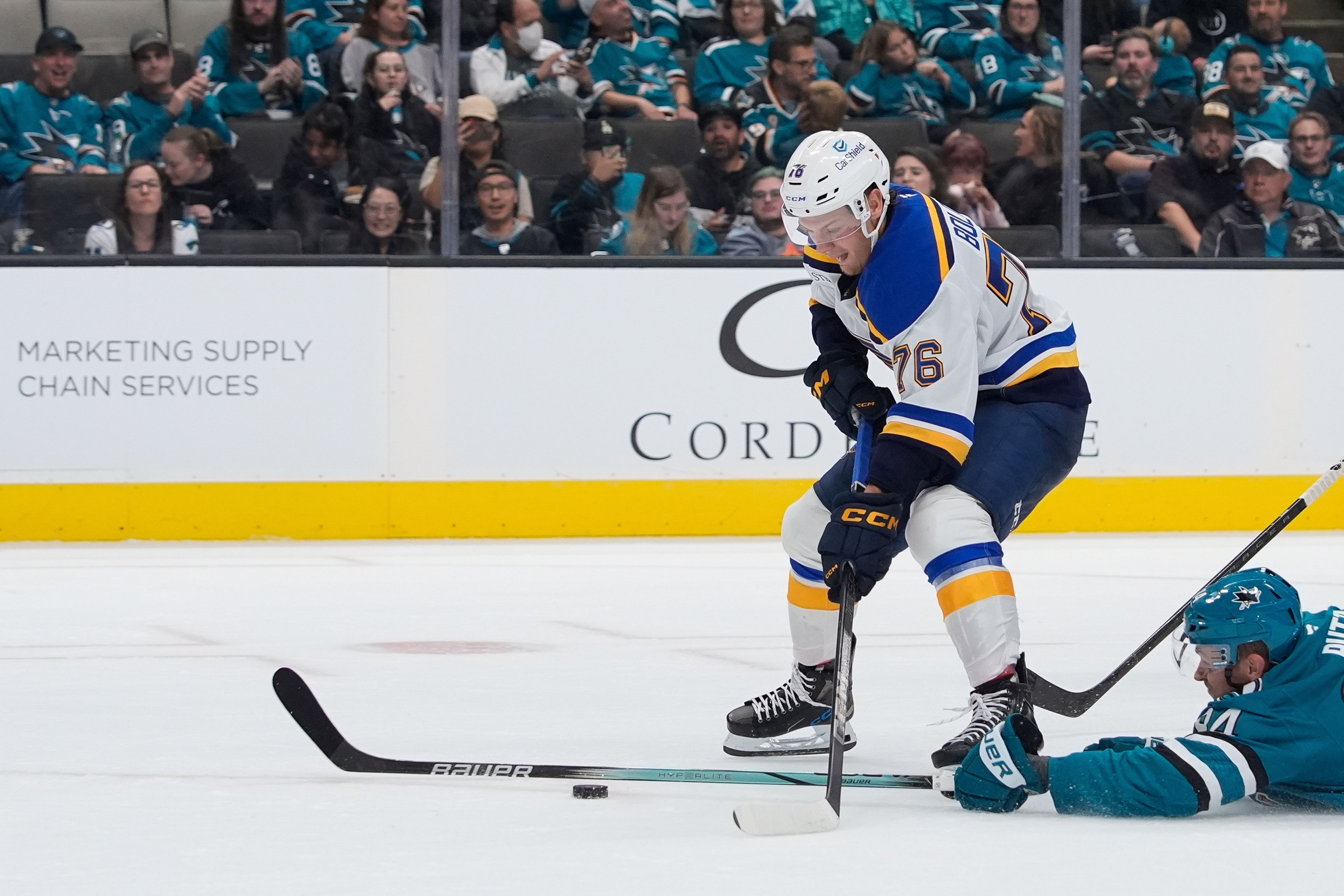 San Jose Sharks defenseman Jan Rutta, bottom, dives as St. Louis Blues center Zack Bolduc (76) moves the puck during the second period of an NHL hockey game Thursday, Oct. 10, 2024, in San Jose, Calif. (AP Photo/Godofredo A. Vásquez)