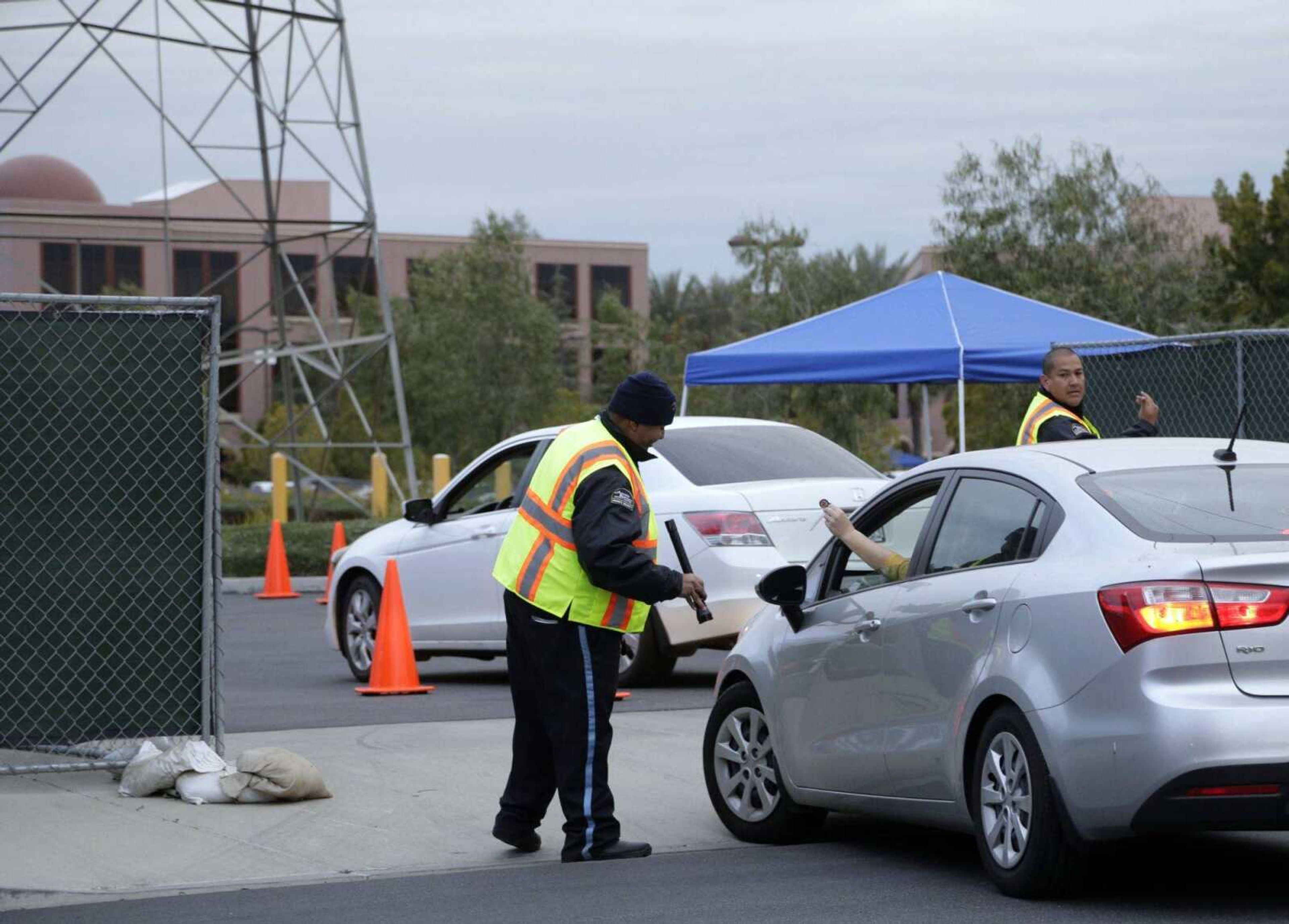 Guards check for IDs as workers return to work Monday at the Inland Regional Center for the first time in San Bernardino, California, where an attack killed 14 people Dec. 2. (Nick Ut ~ Associated Press)