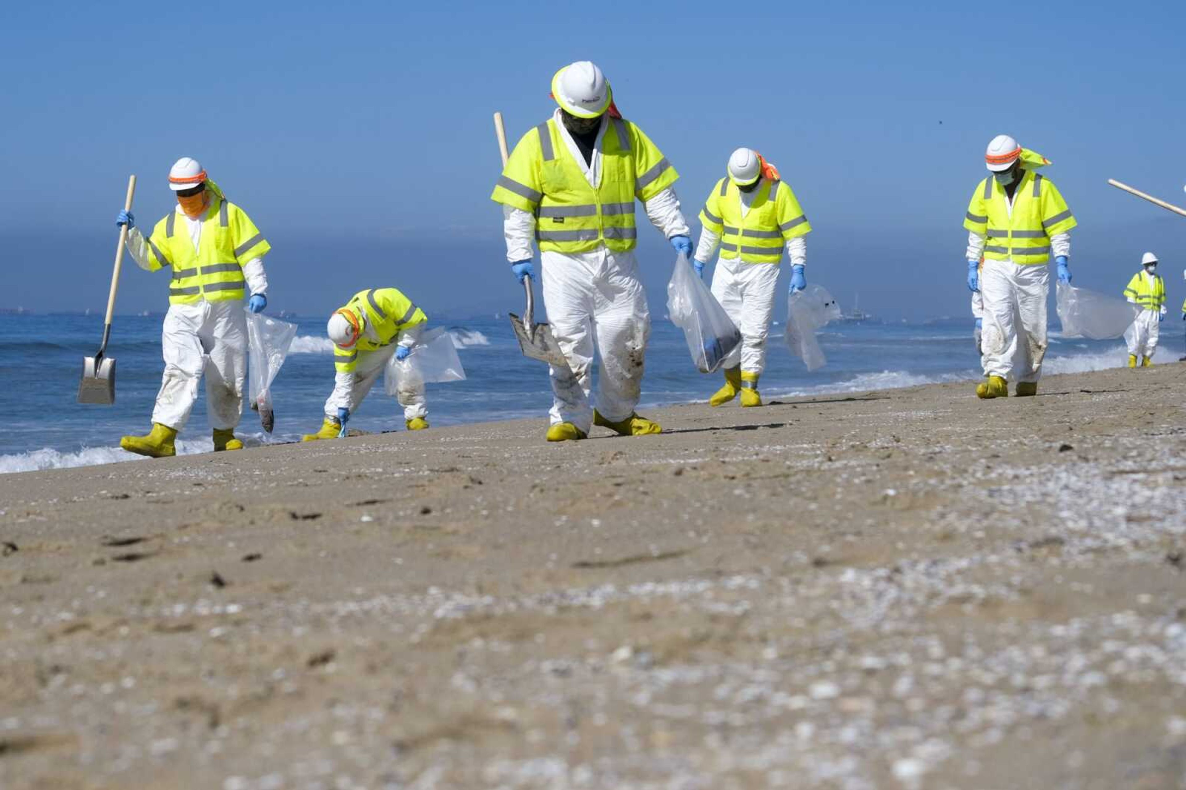 Workers in protective suits clean the contaminated beach Tuesday after an oil spill in Huntington Beach, California. The Coast Guard received the first report of a possible oil spill off the Southern California coast more than 12 hours before a company reported a major leak in its pipeline and a cleanup effort was launched, records show.