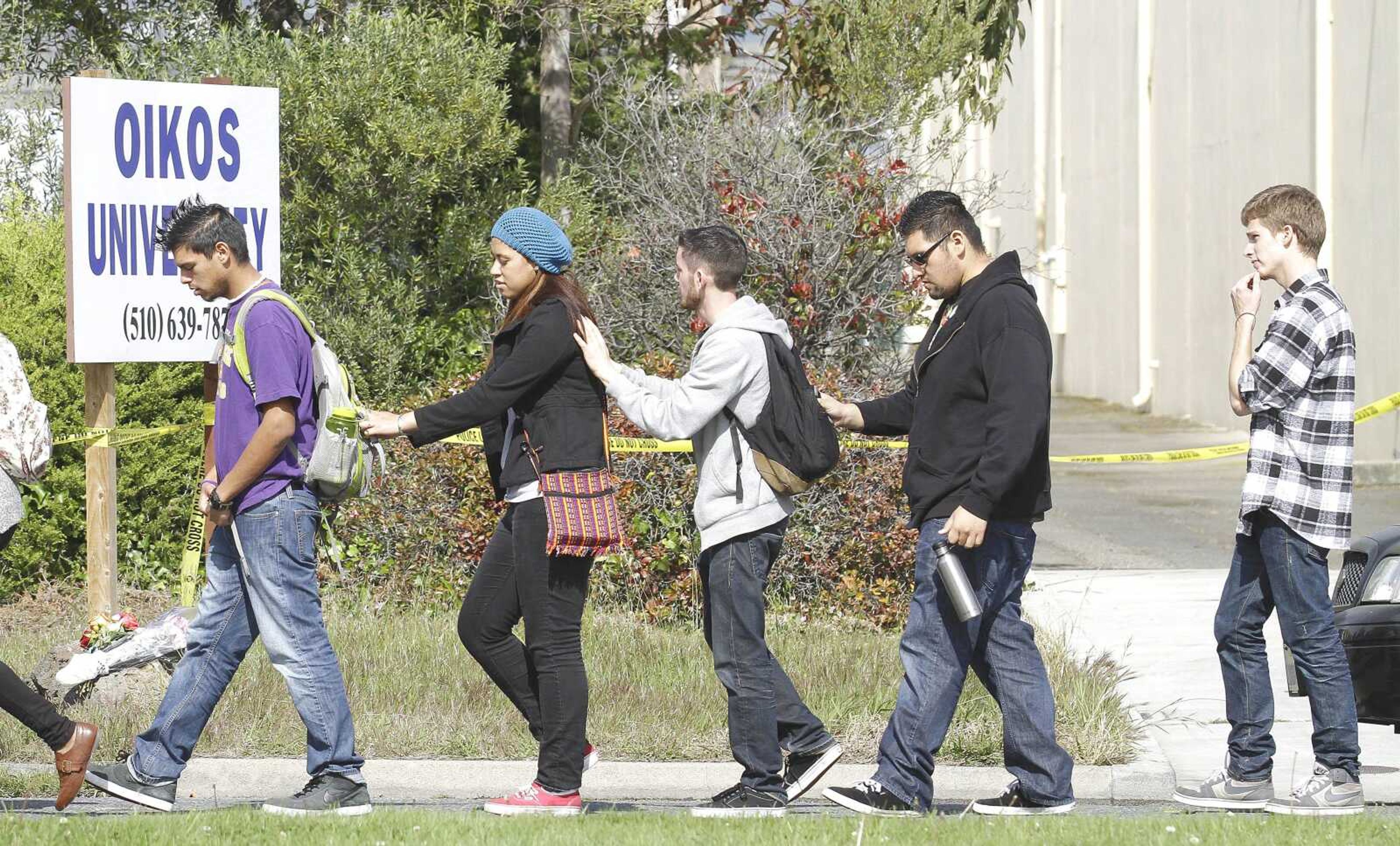 Students from School of Urban Missions, a Bible college, pray Tuesday as they walk past Oikos University in Oakland, Calif. A South Korean-born student expelled from a small Christian university and upset about being teased over his poor English skills opened fire at the school, going from room to room in a rampage that left six students and a secretary dead, police said Tuesday. (Jeff Chiu ~ Associated Press)